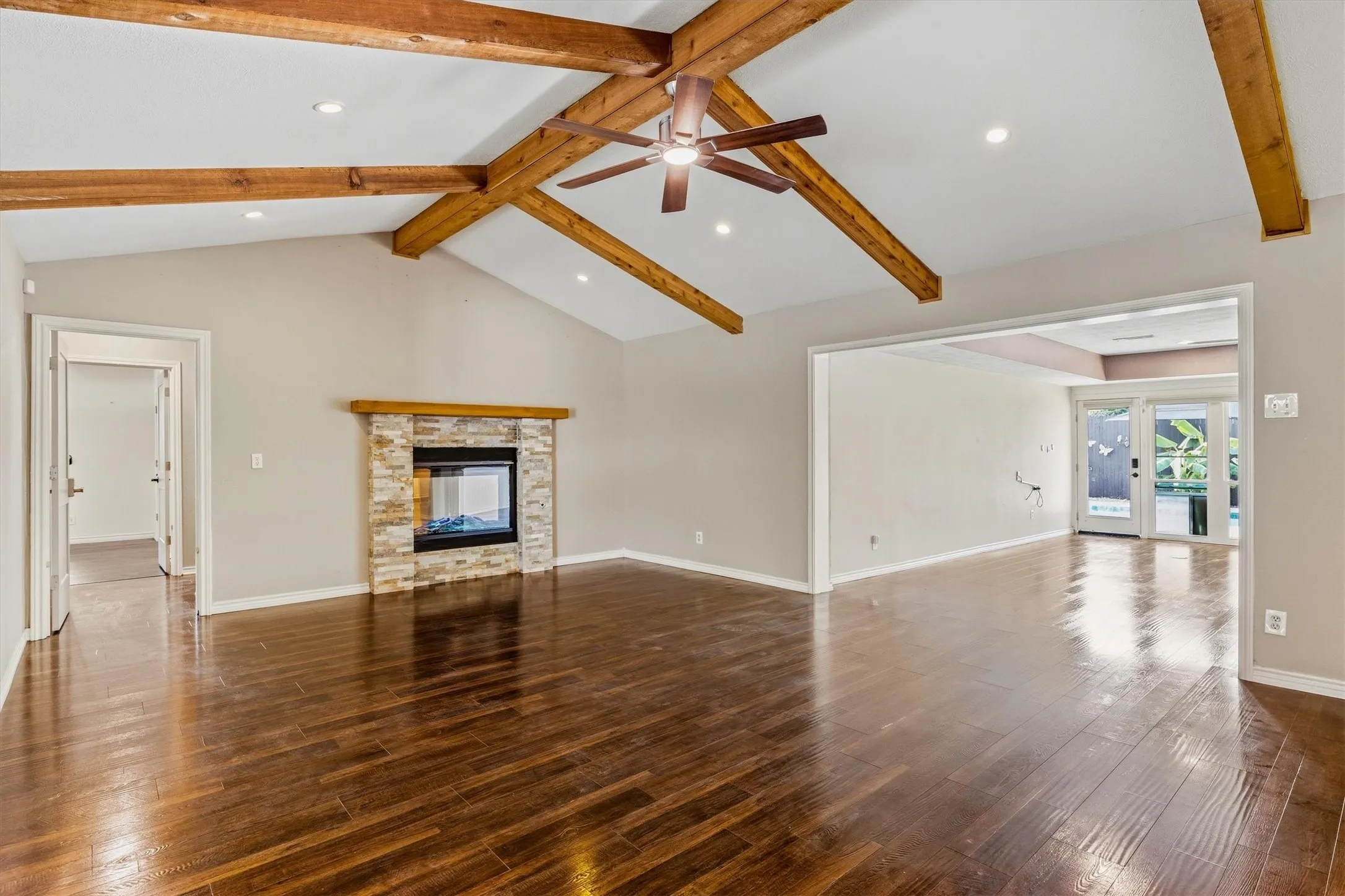 Vaulted ceiling with exposed wood beams, recessed lighting, and a ceiling fan