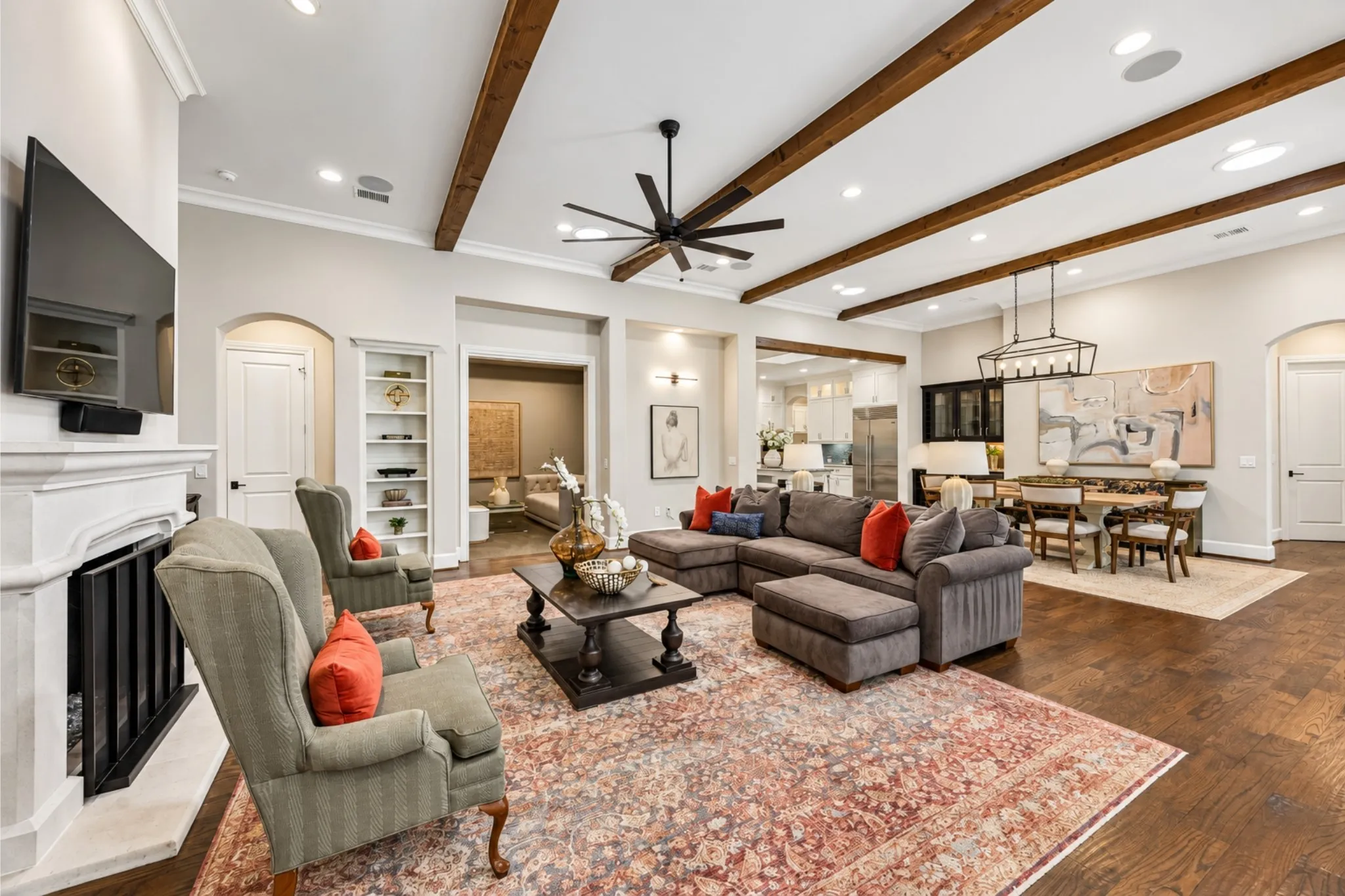 Exposed ceiling beams, recessed lighting, fireplace with mantel, dark wood-finish flooring, and built-in shelving