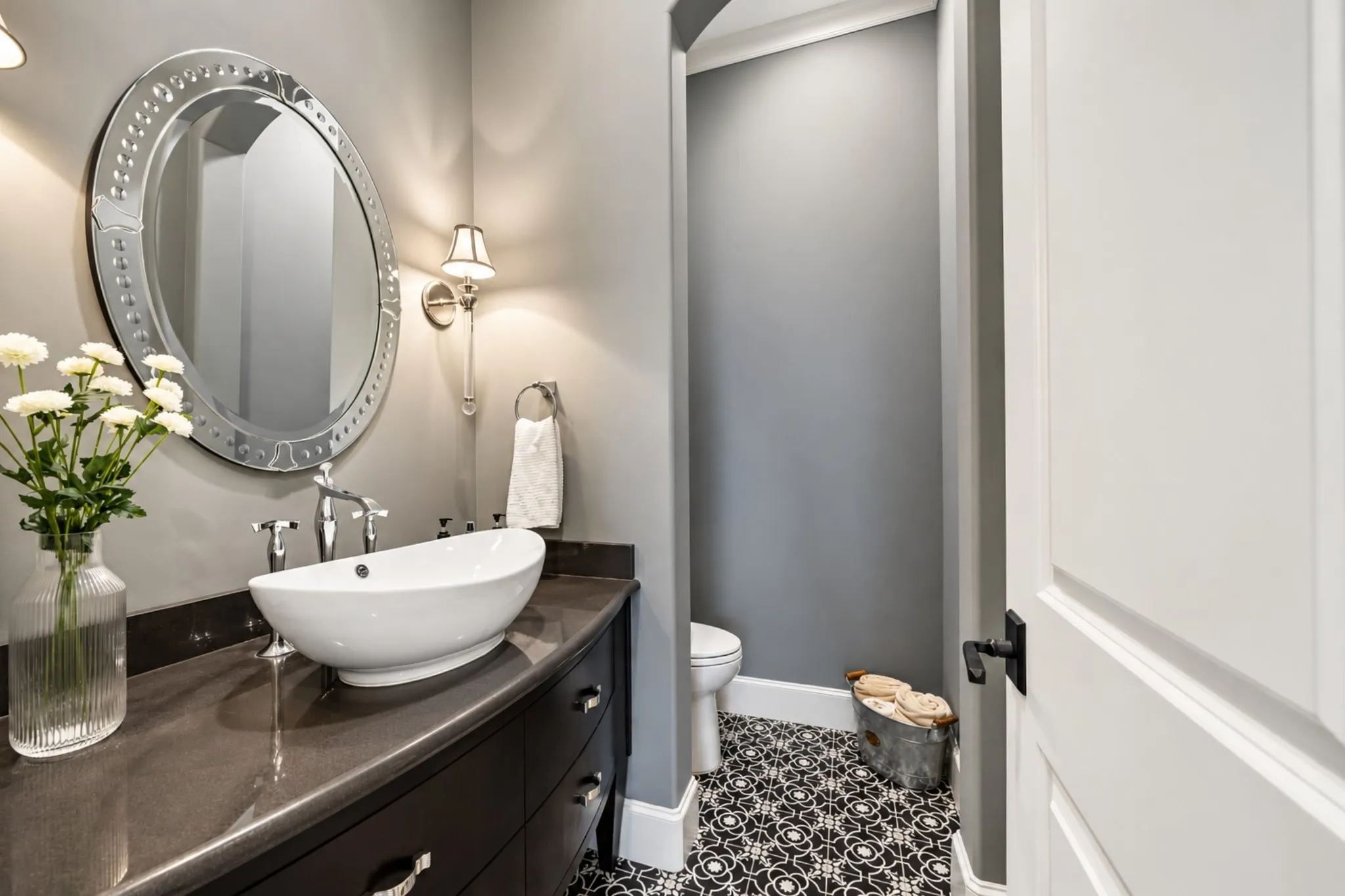 Floating vanity with a vessel sink, chrome fixtures, and a decorative oval mirror