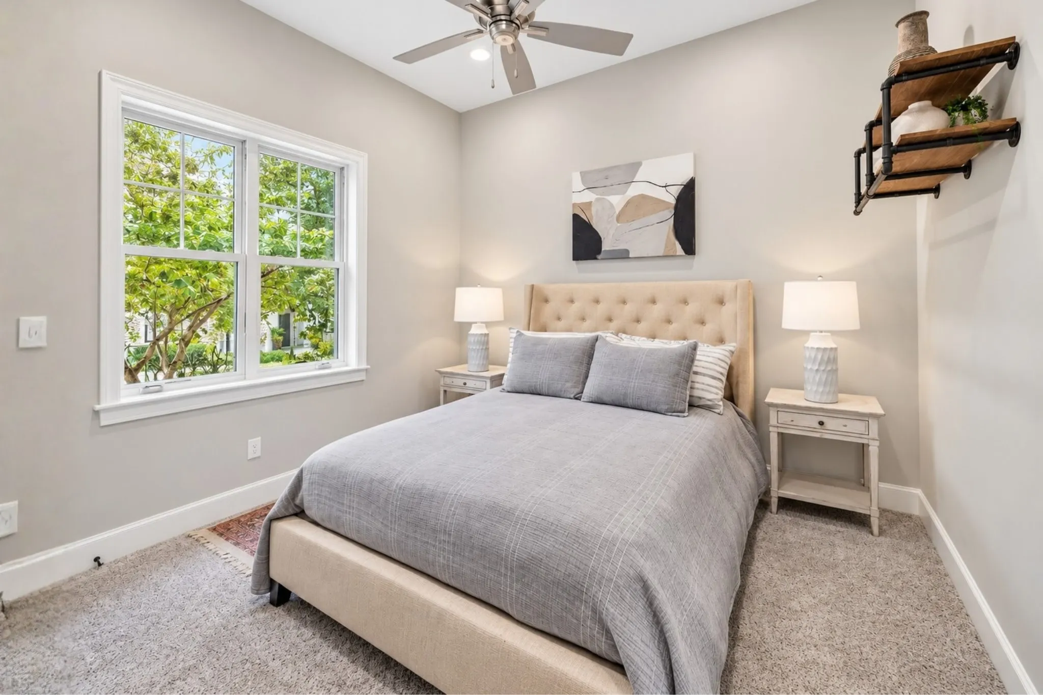 Carpeted flooring, window with gridded panes, ceiling fan, neutral wall tones, built-in wall shelving