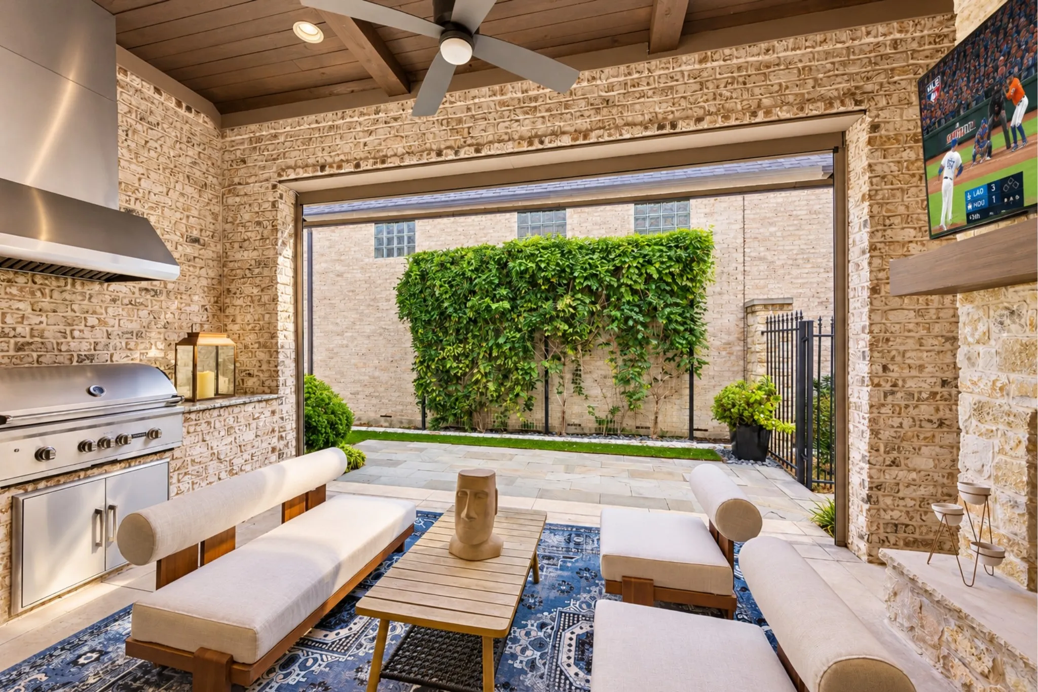 Covered outdoor patio with a built-in grill, ceiling fan, and exposed wood beam ceiling