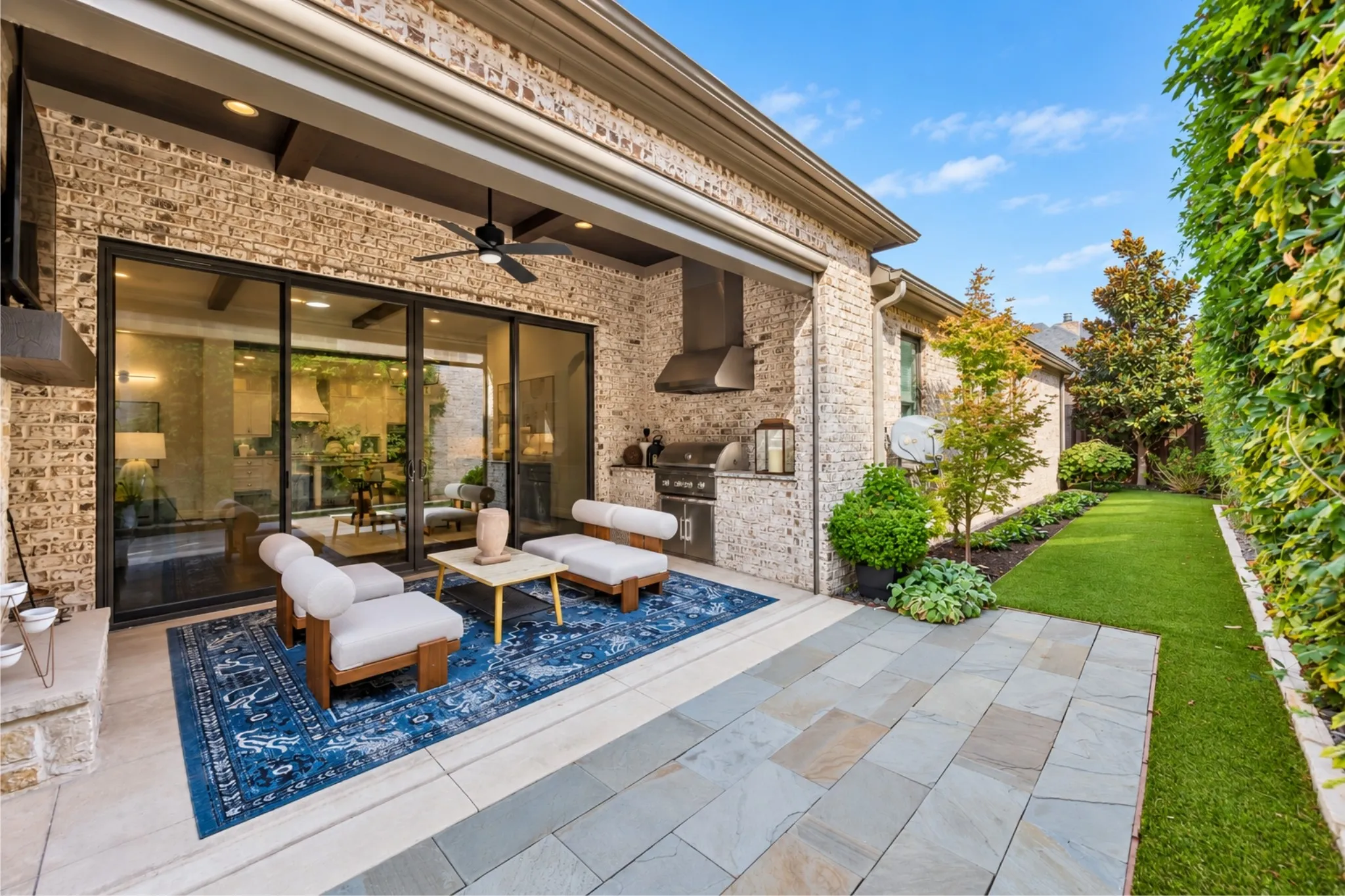 Expansive patio featuring a built-in outdoor kitchen, ceiling fan, and large sliding glass doors
