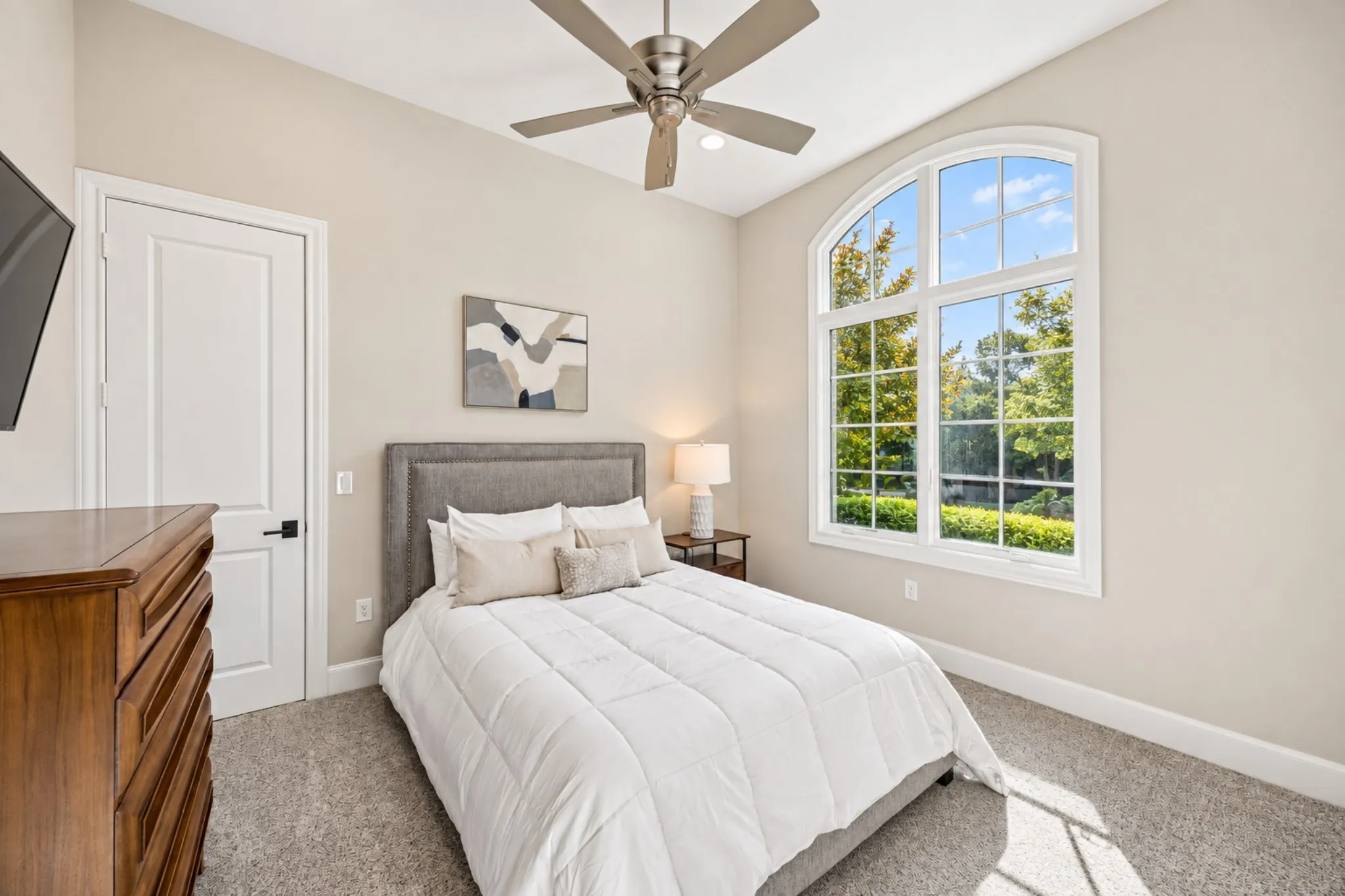 Vaulted ceiling with a ceiling fan, arched window with gridded panes, light-toned wall paint, and gray carpet flooring