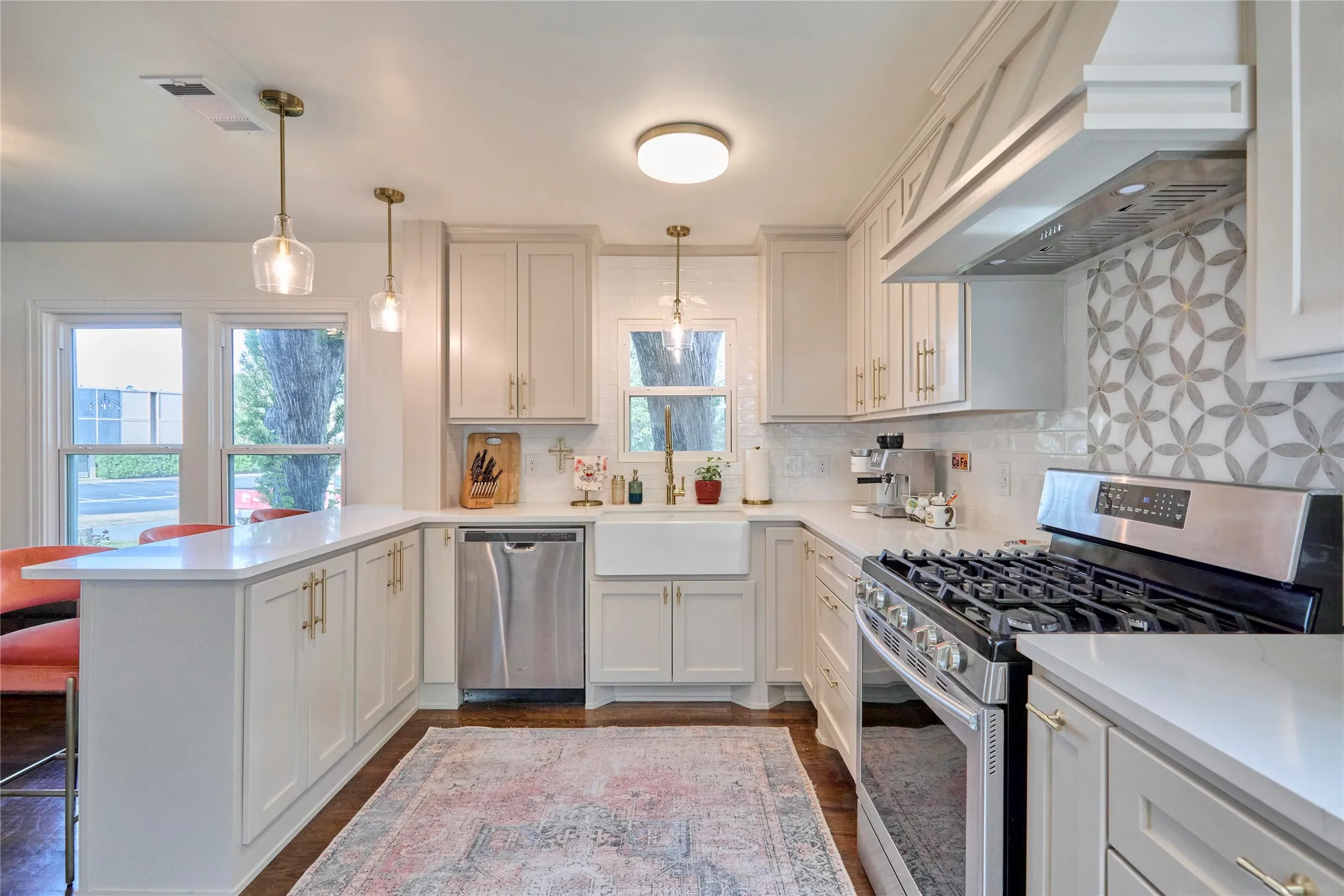 White shaker cabinetry with gold-finish hardware, stainless steel appliances, a gas range, and a decorative tile backsplash