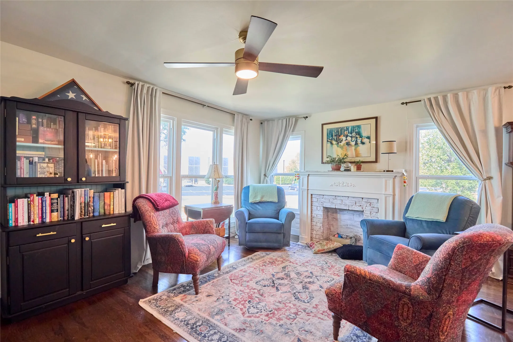 Living space with wood-finish flooring, a ceiling fan with integrated lighting, and multiple windows