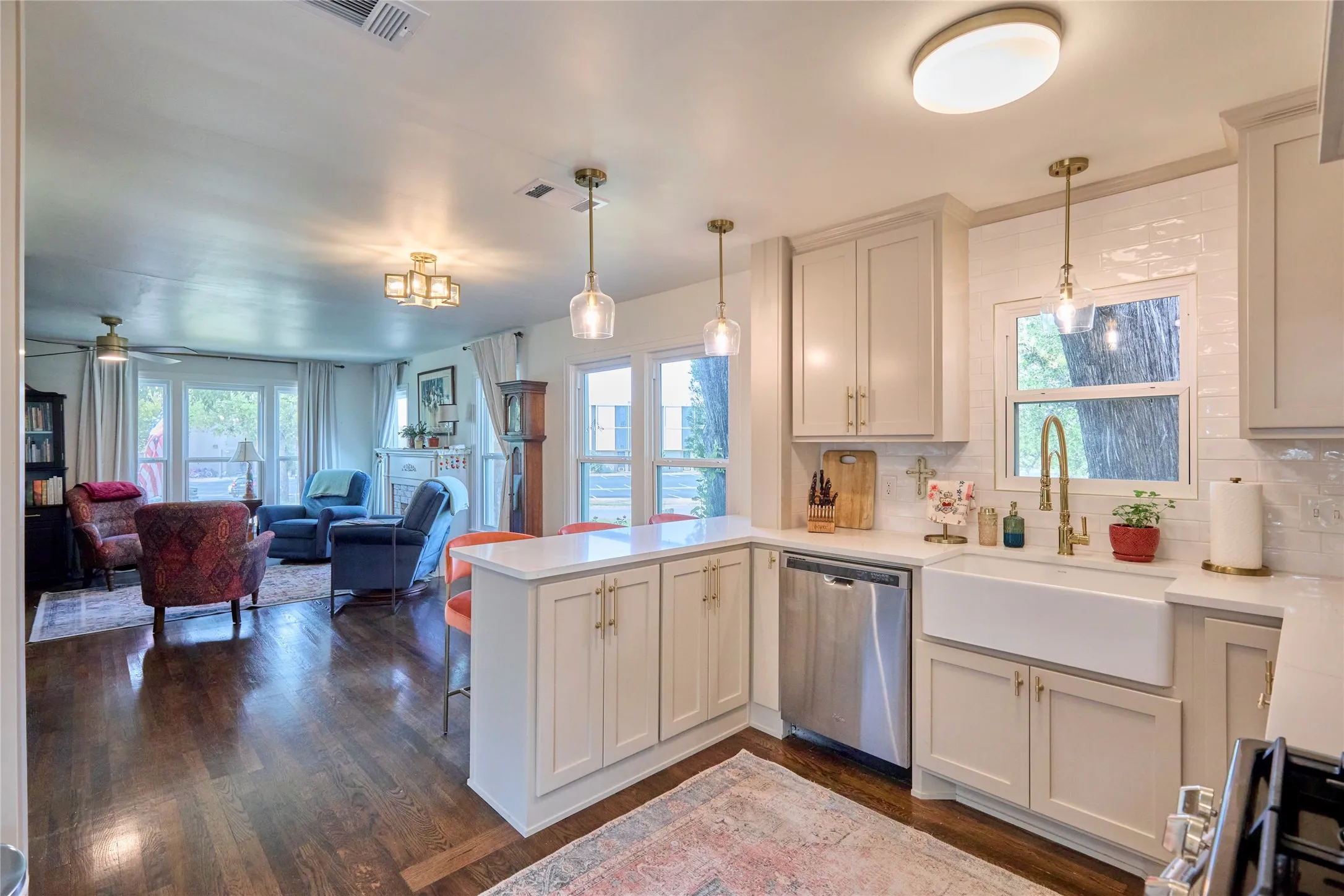 Gourmet kitchen with white cabinetry, stainless steel dishwasher, farmhouse sink, and brass fixtures