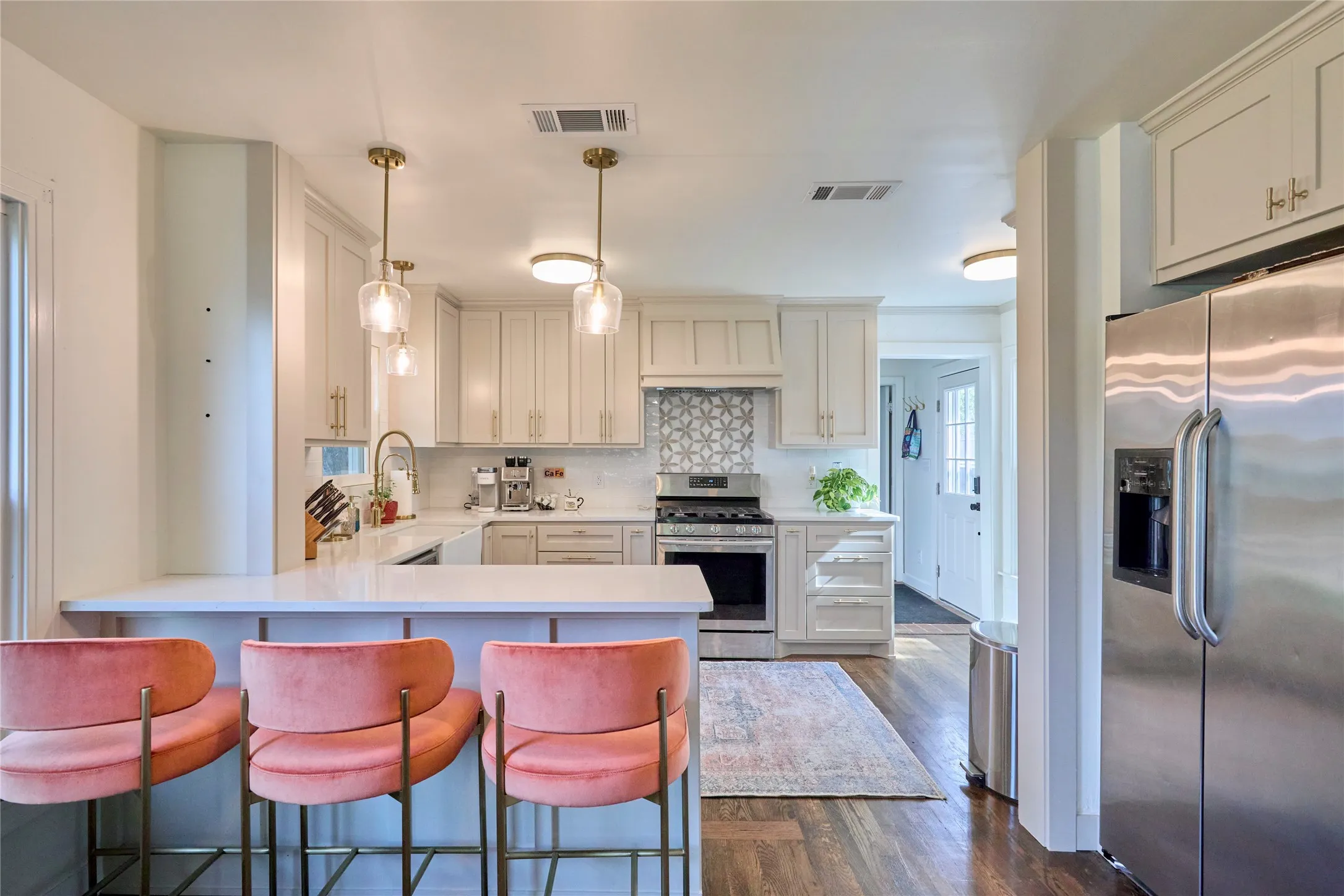 White shaker cabinetry, stainless steel appliances, wood-finish flooring, recessed lighting, and a patterned tile backsplash