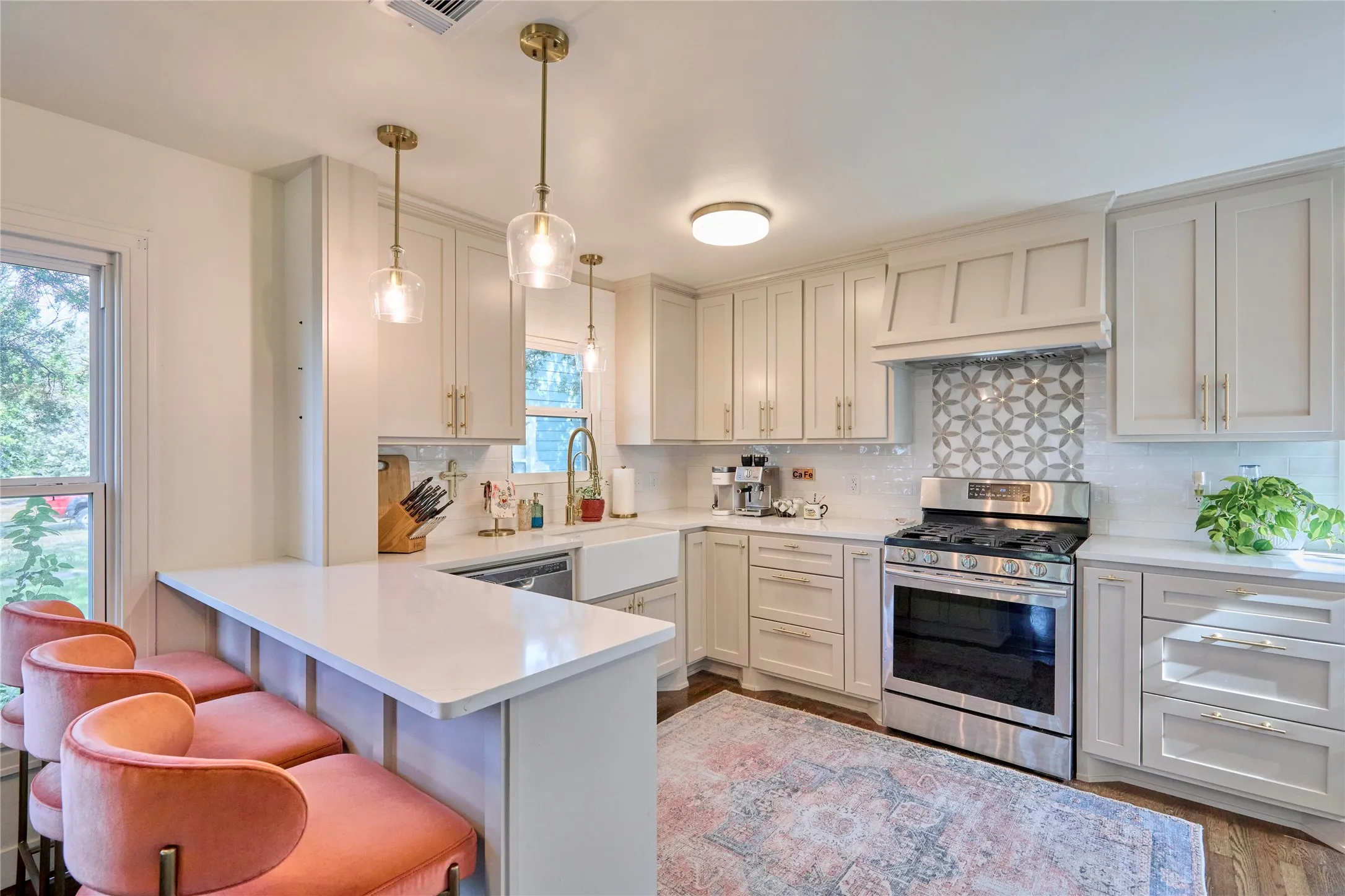 White shaker cabinetry, stainless steel range, white farmhouse sink, white countertops, and decorative tile backsplash