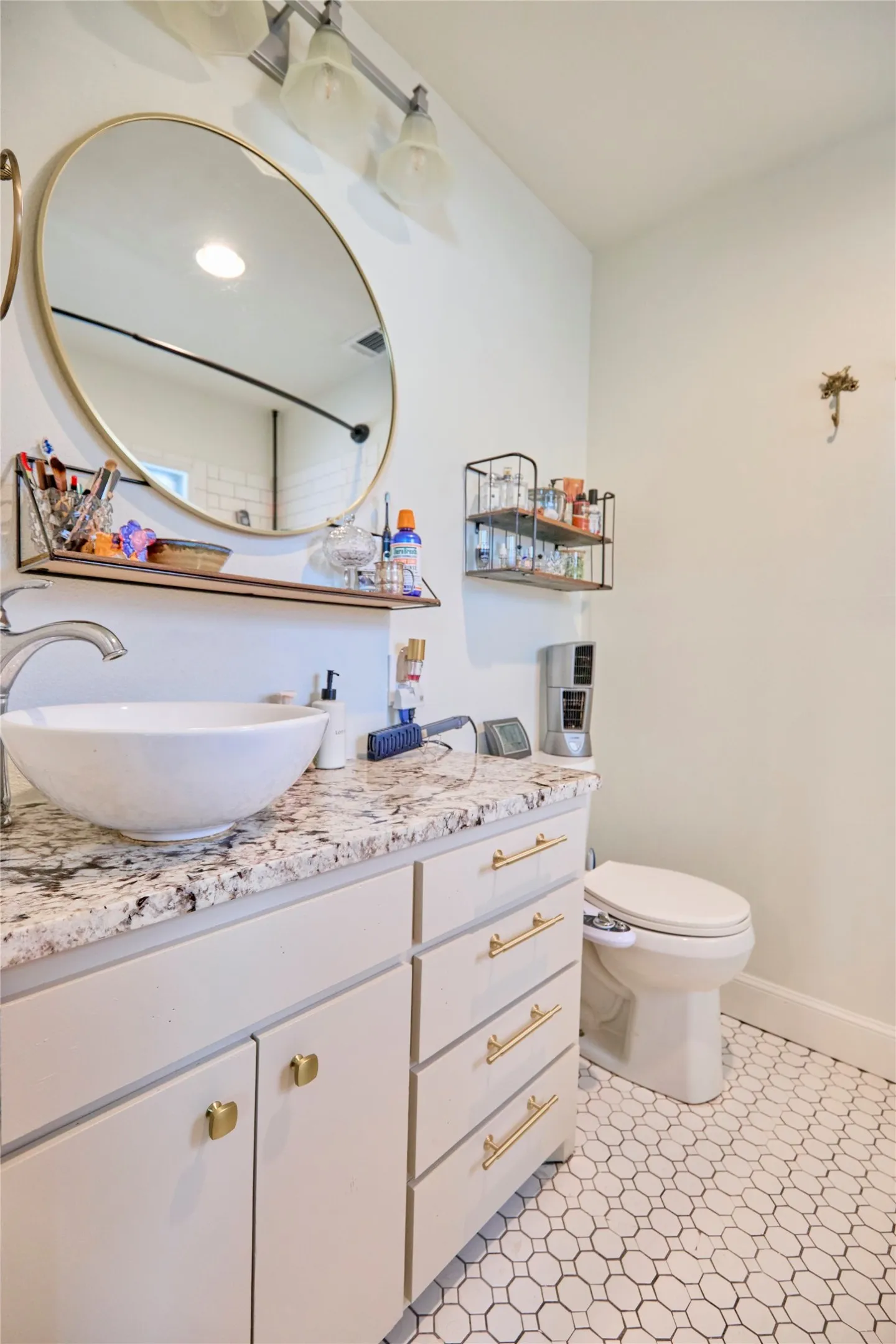 White vanity with gold hardware, granite-style countertop, and vessel sink