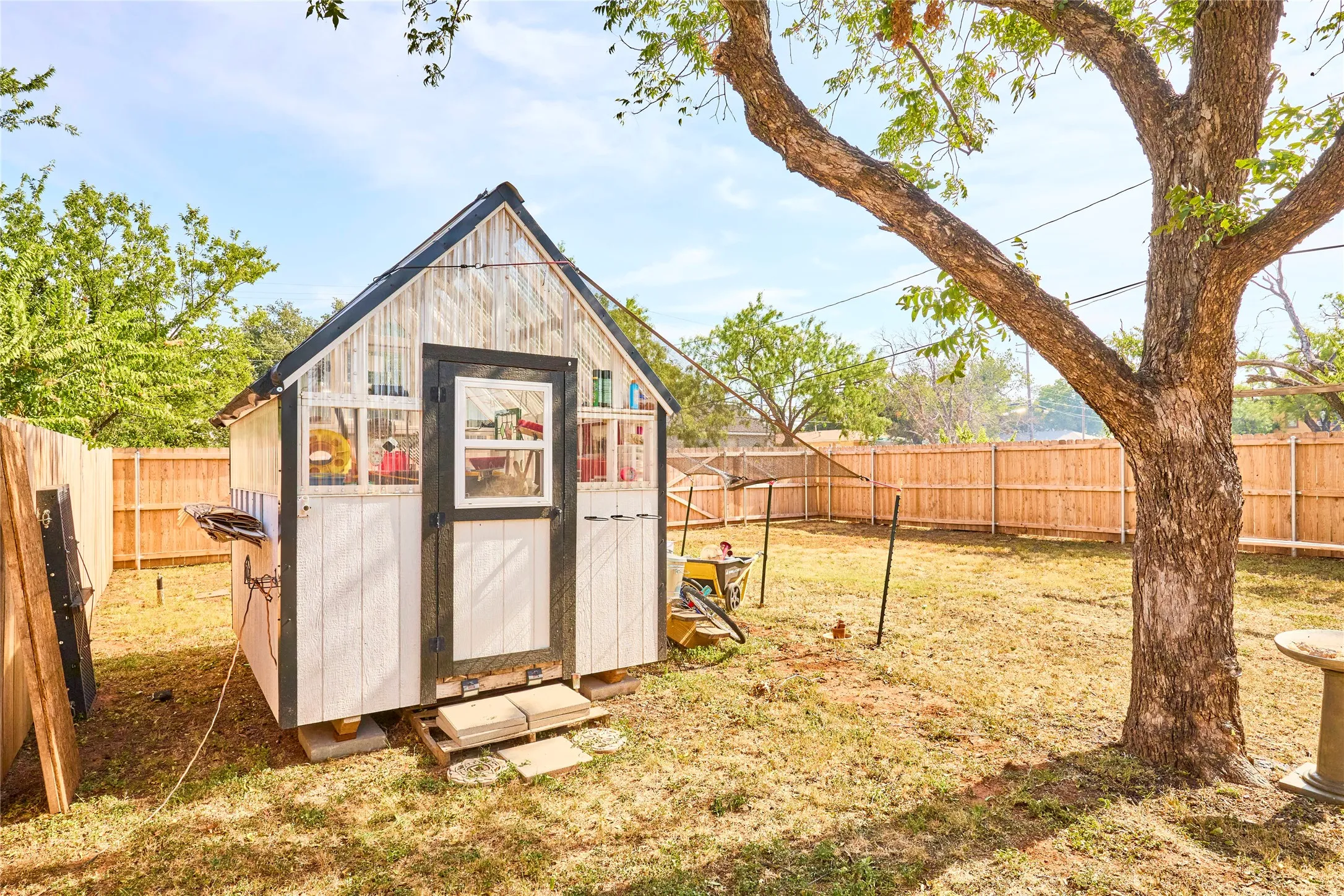 Backyard with a detached shed, natural wood privacy fencing, and a mature tree