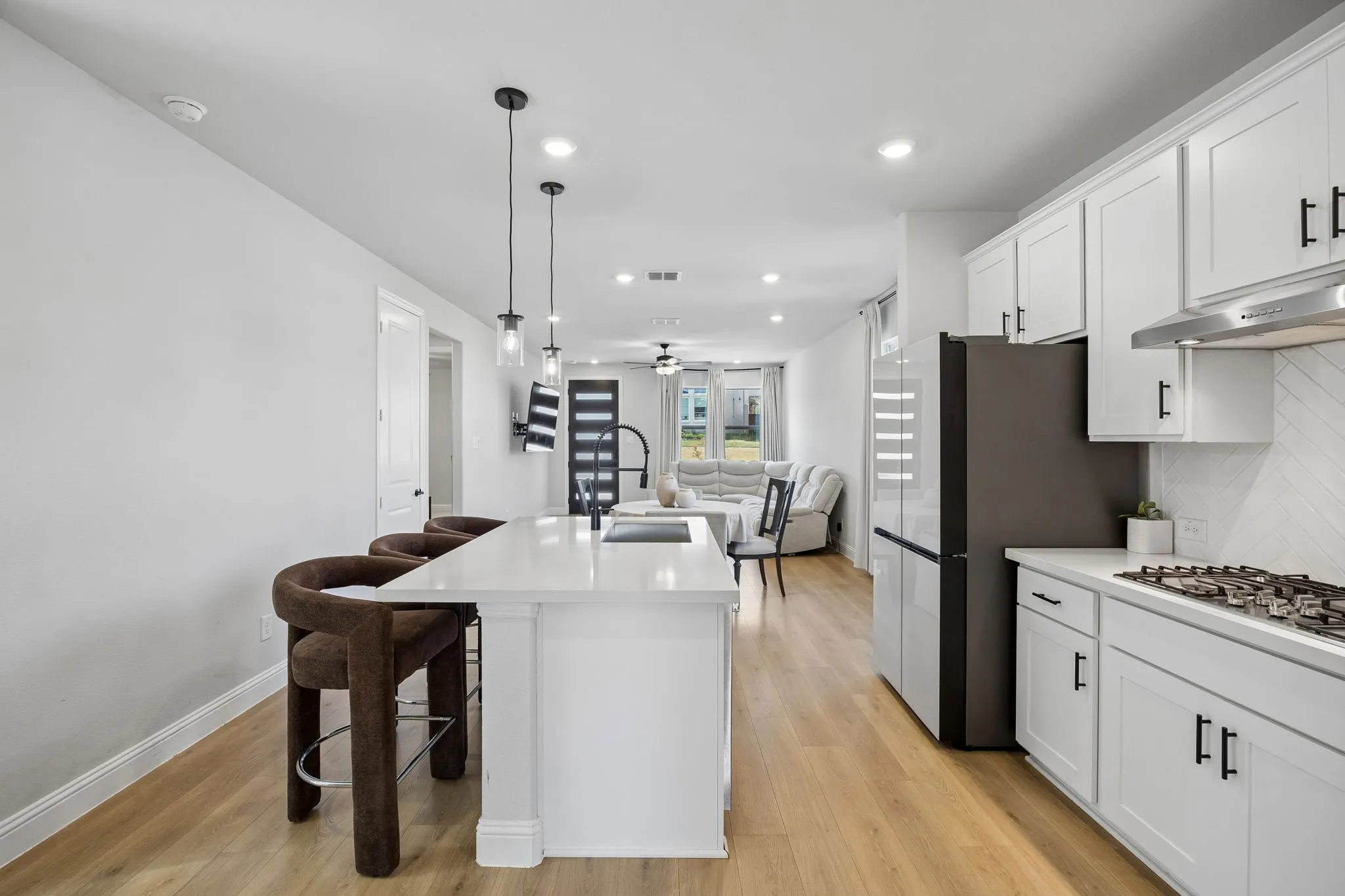 Kitchen featuring white cabinetry, light-tone wood-finish flooring, recessed lighting, and a kitchen island with pendant lighting