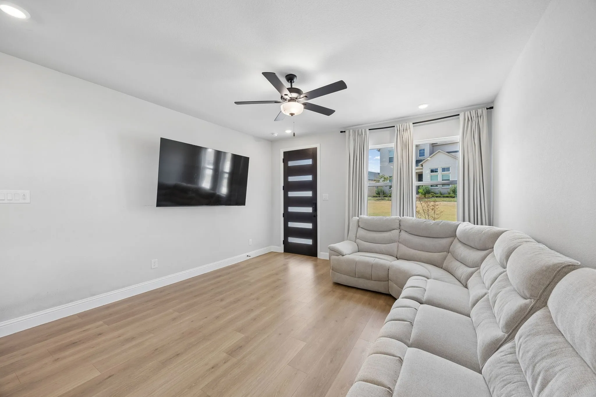 Recessed lighting, wood-finish flooring, and a modern ceiling fan with integrated lighting