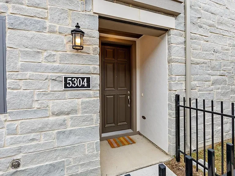 Stone veneer exterior with a recessed entryway, paneled front door, and an exterior wall lantern