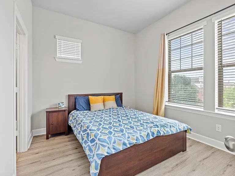 Wood-finish flooring, multiple windows with blinds, and white trim