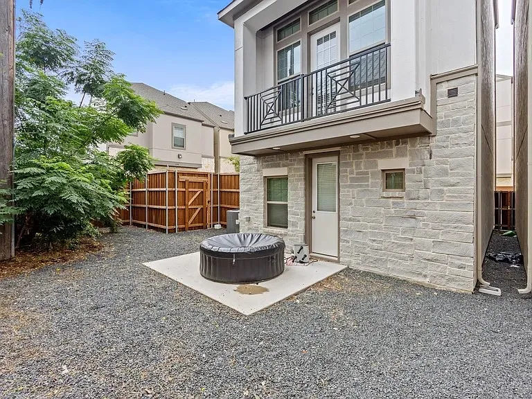 Exterior featuring stone cladding, a second-story balcony with metal railing, and a ground-level access door