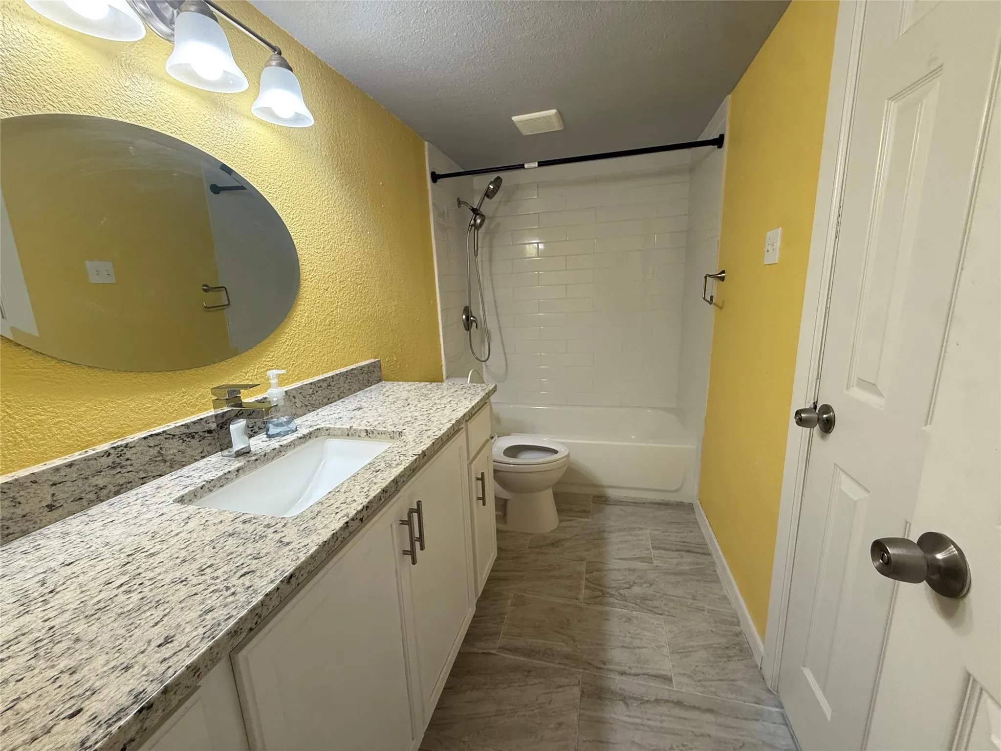 Spacious vanity with an integrated sink and light-toned countertop, complemented by a large oval mirror
