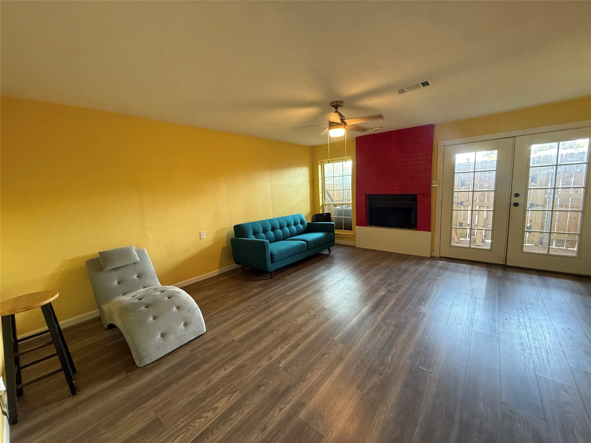 Wood-finish flooring, built-in fireplace, ceiling fan, and French doors with multiple panes