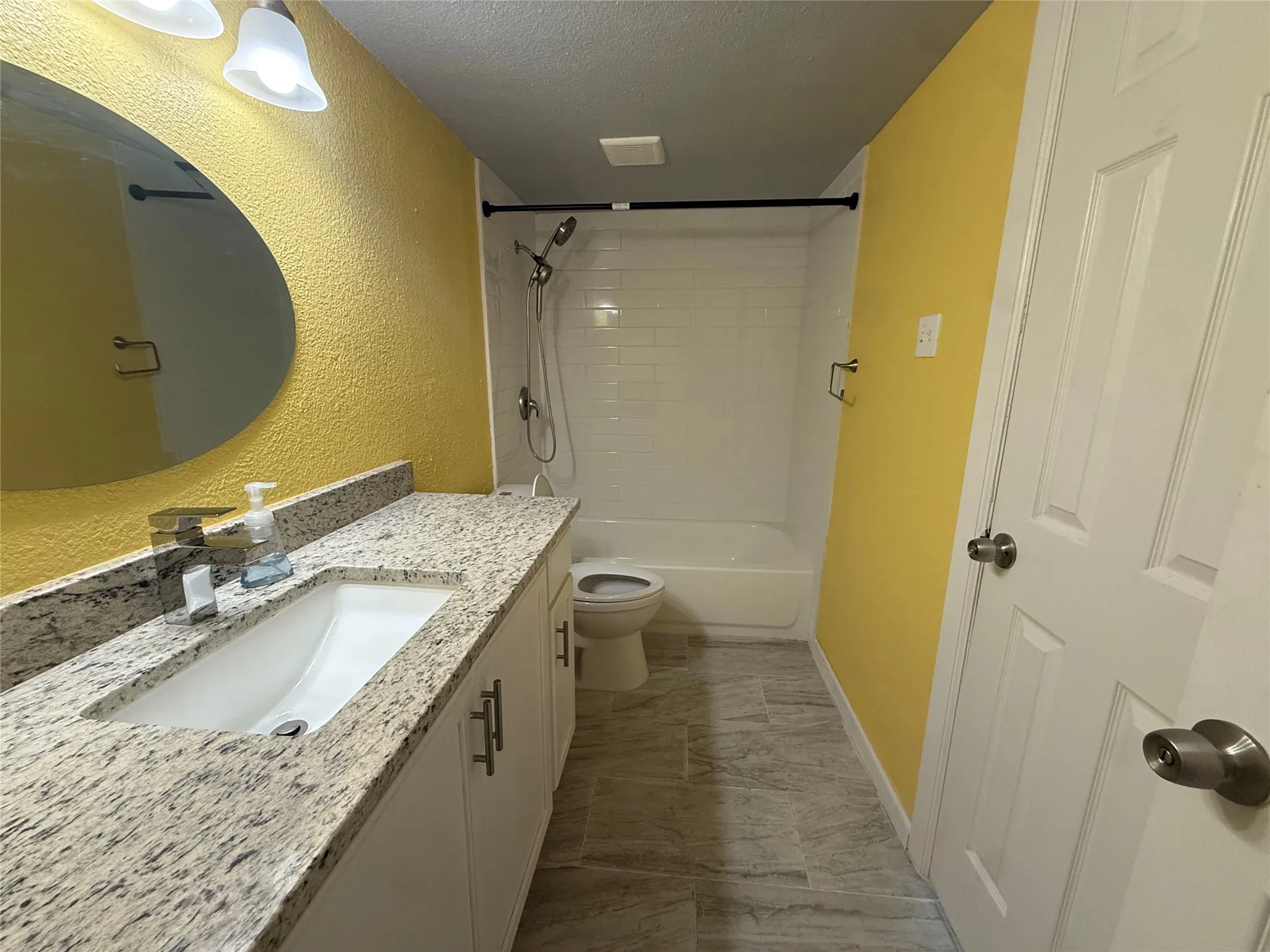 Bathroom featuring a white vanity with an undermount sink, a light-toned countertop, and a built-in bathtub with a shower