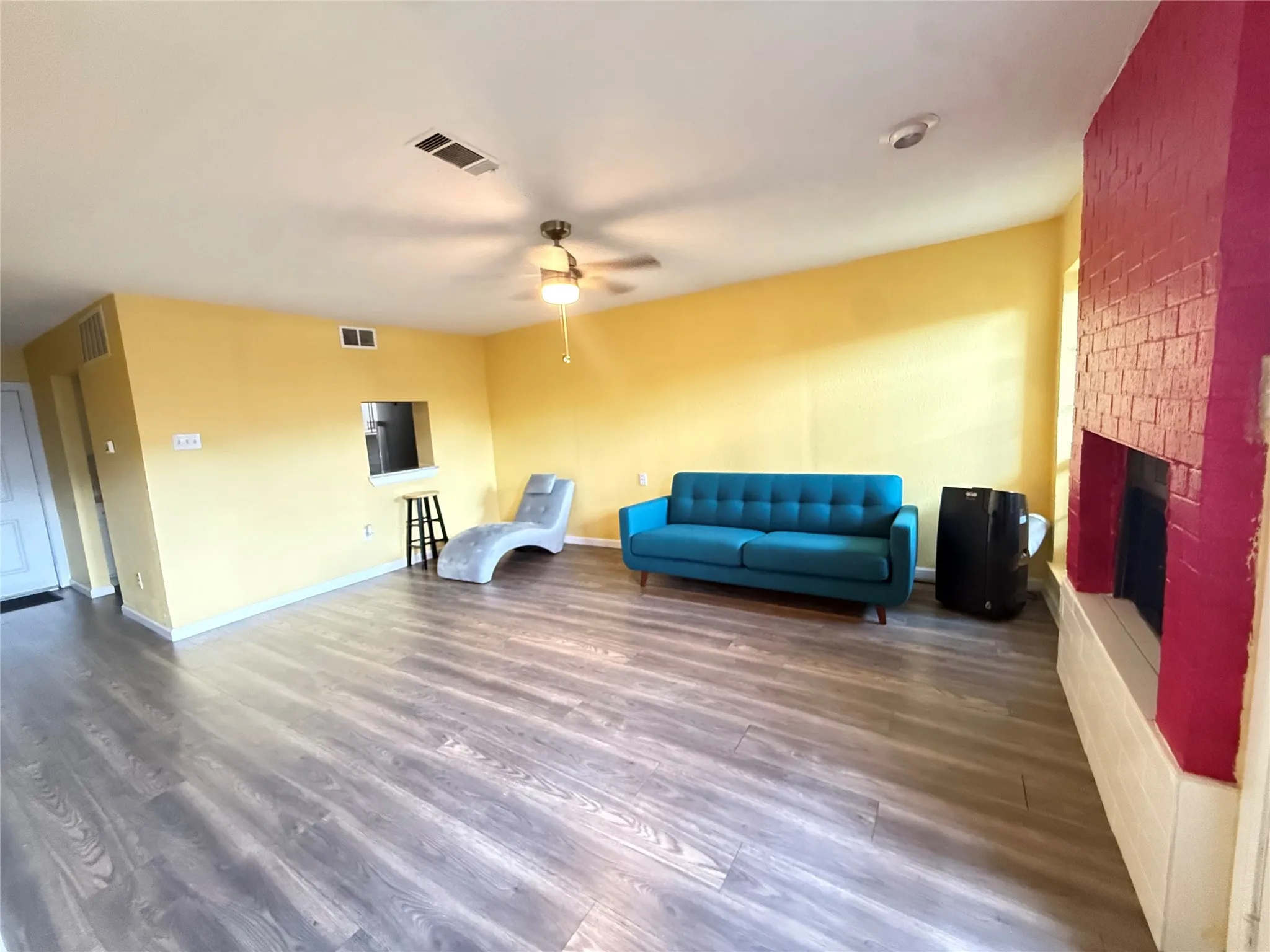 Living area featuring wood-finish flooring, a painted brick fireplace, a ceiling fan, and recessed lighting