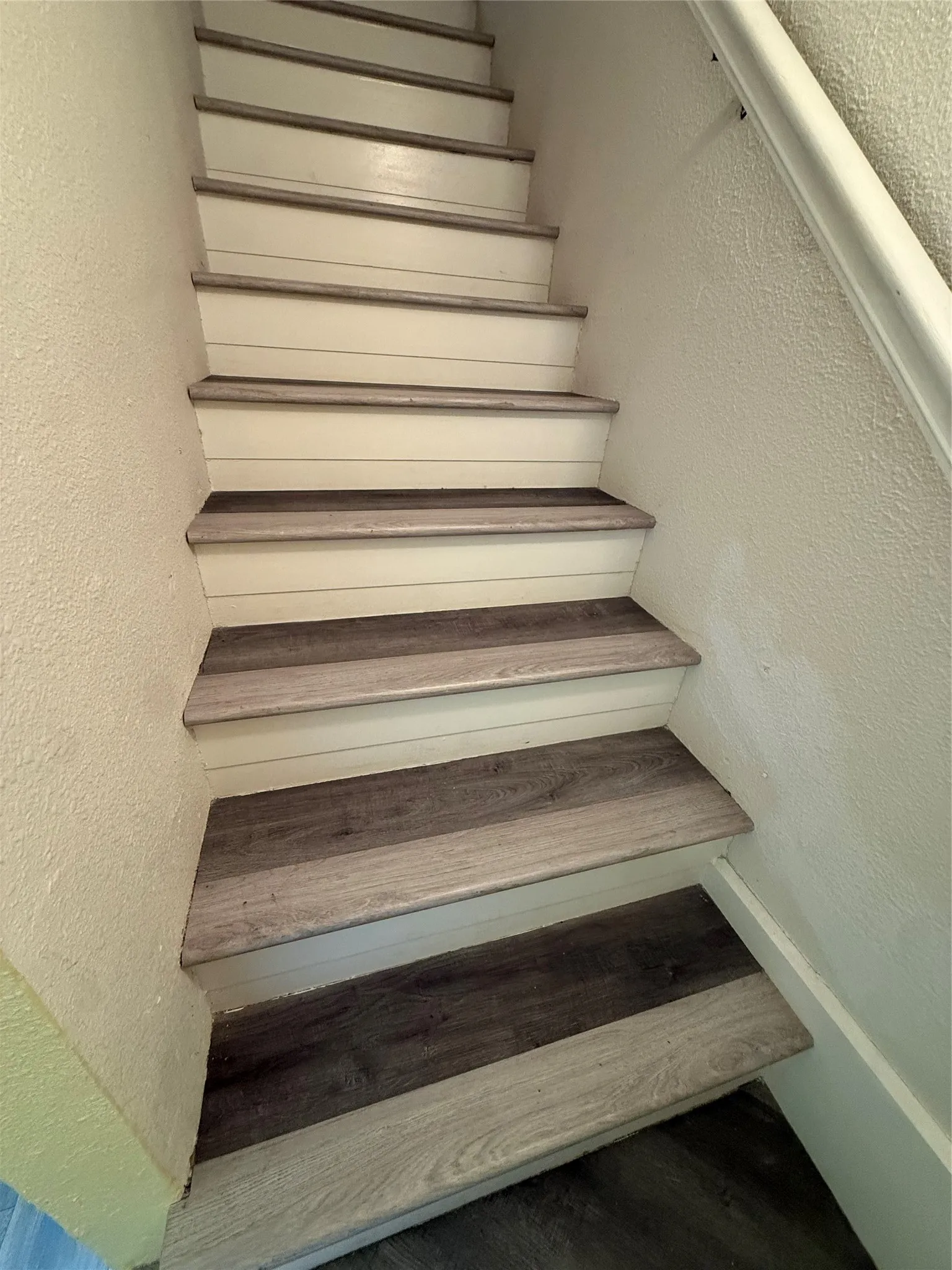 Staircase featuring wood-finish treads and risers, with a white painted handrail