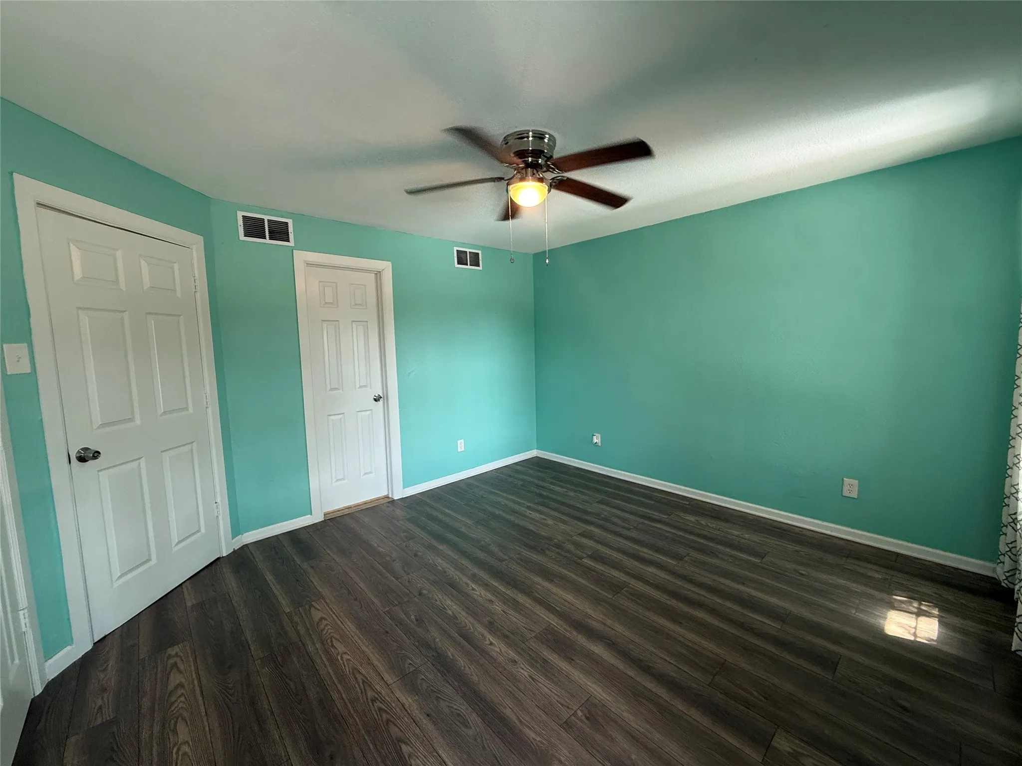 Wood-finish flooring with a ceiling fan and overhead lighting