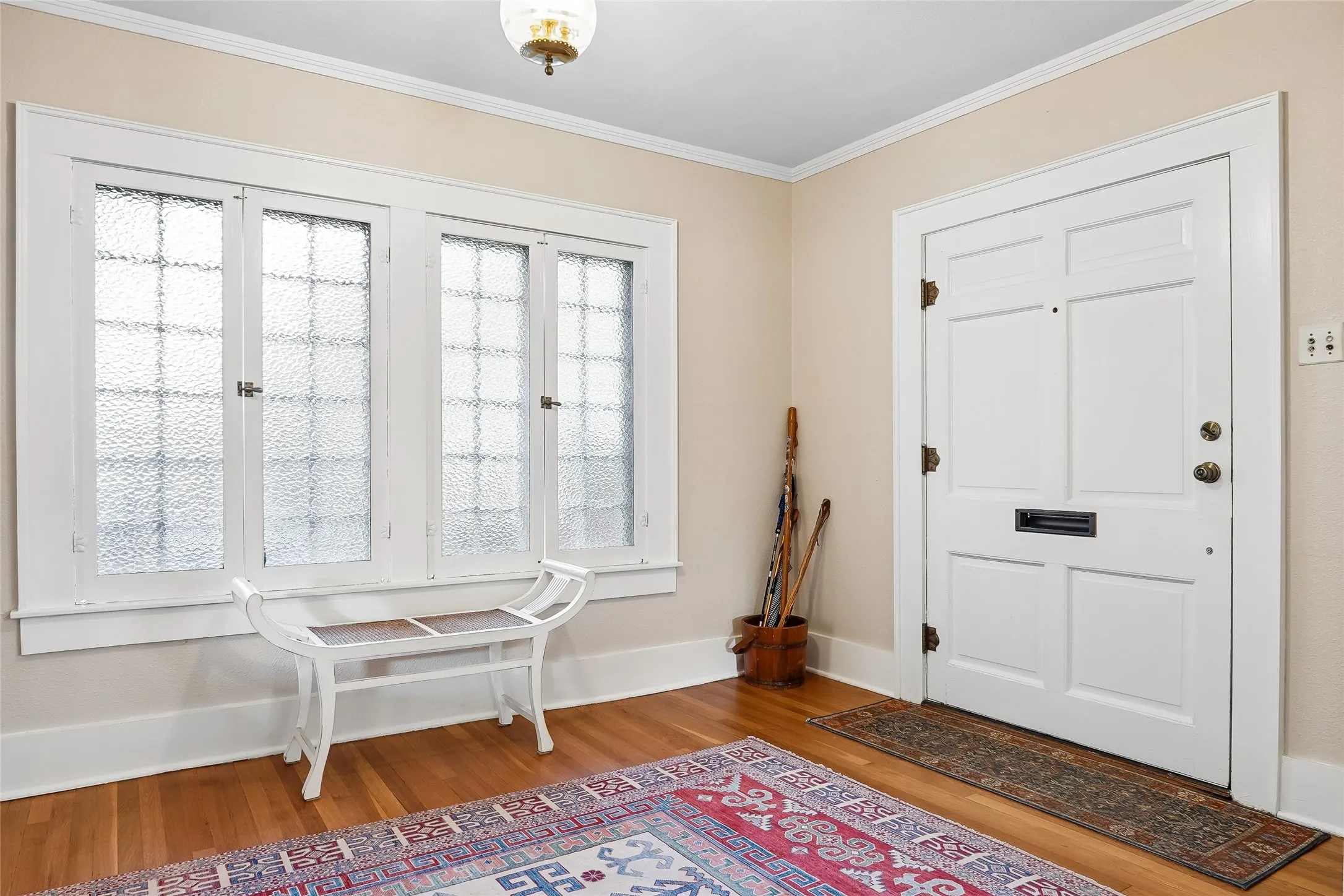 Entryway featuring wood flooring, a white paneled door, and multiple windows with textured glass