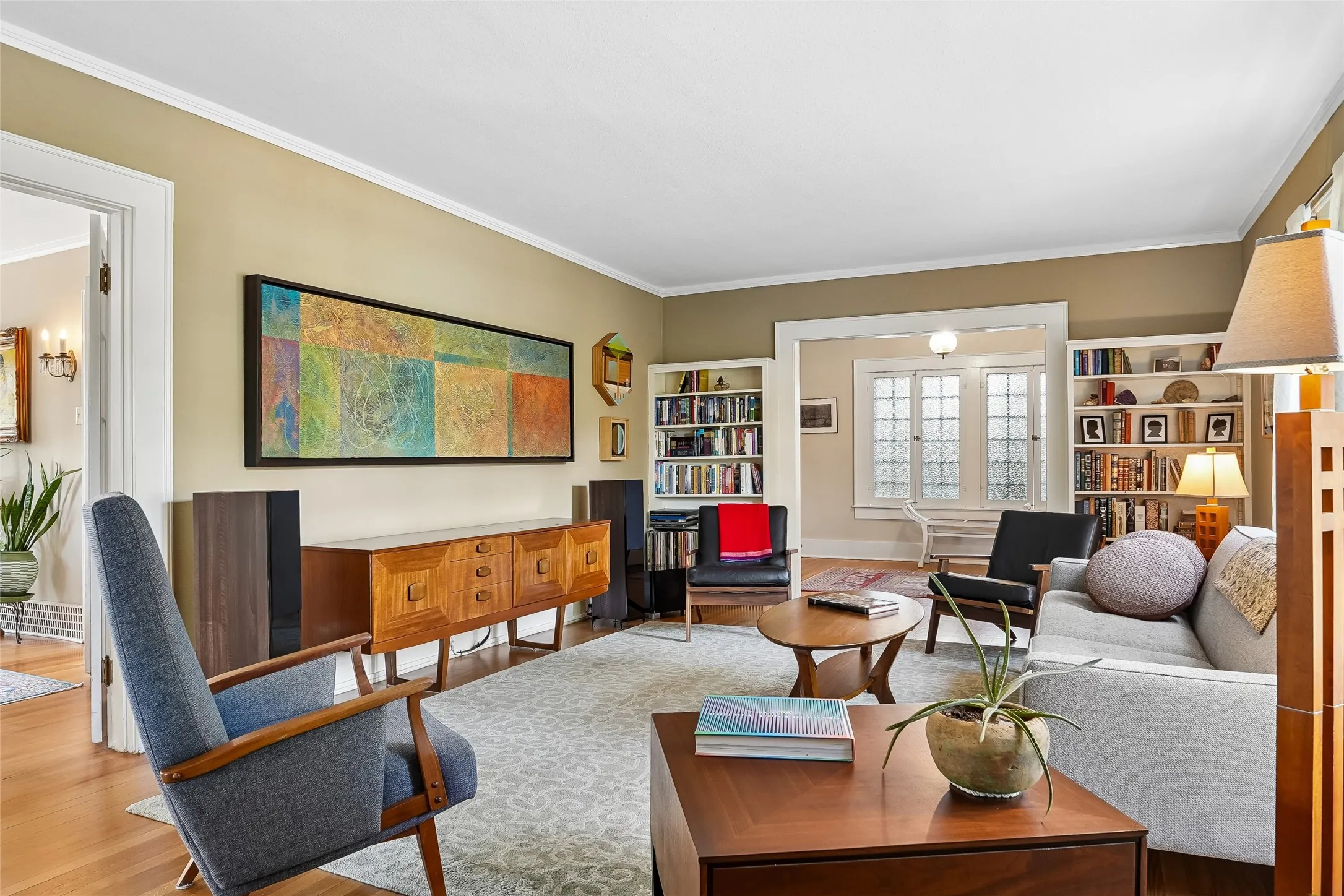 Hardwood flooring, crown molding, built-in shelving, and a decorative frosted glass window
