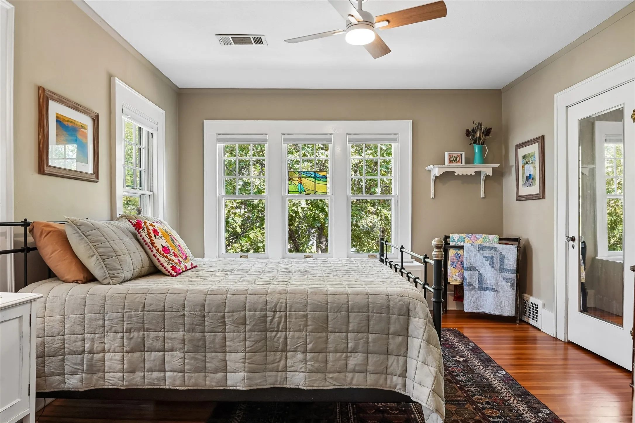 Room featuring wood-finish flooring, a ceiling fan with integrated lighting, and white trim