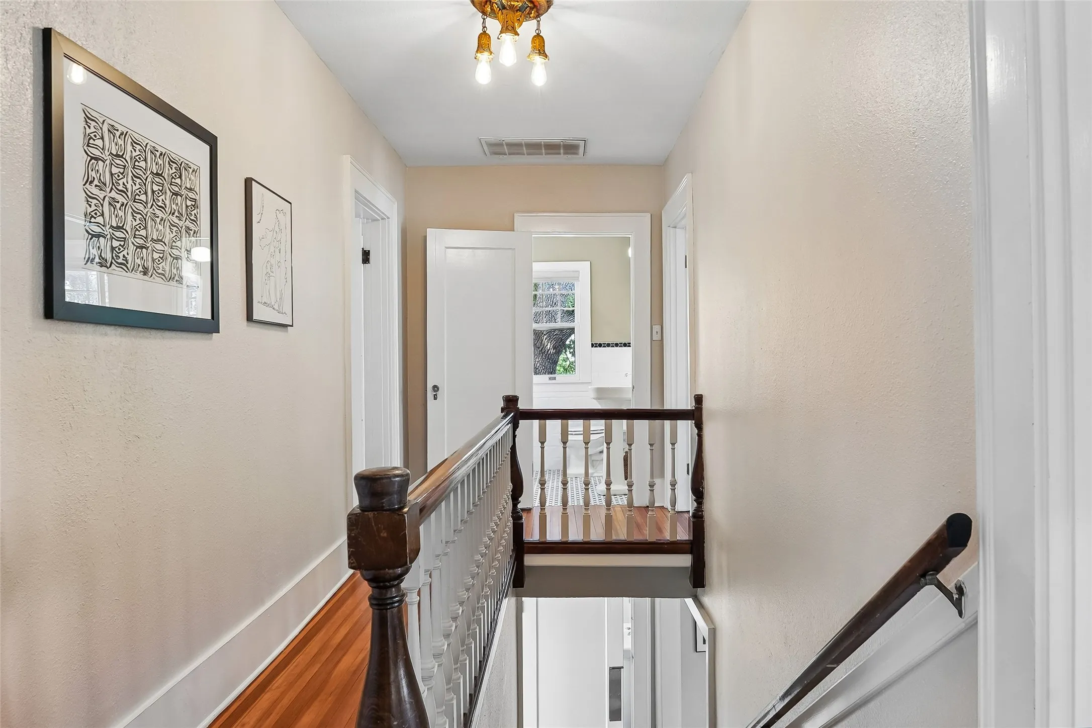 Hardwood flooring throughout, classic baluster staircase, and brass ceiling fixture