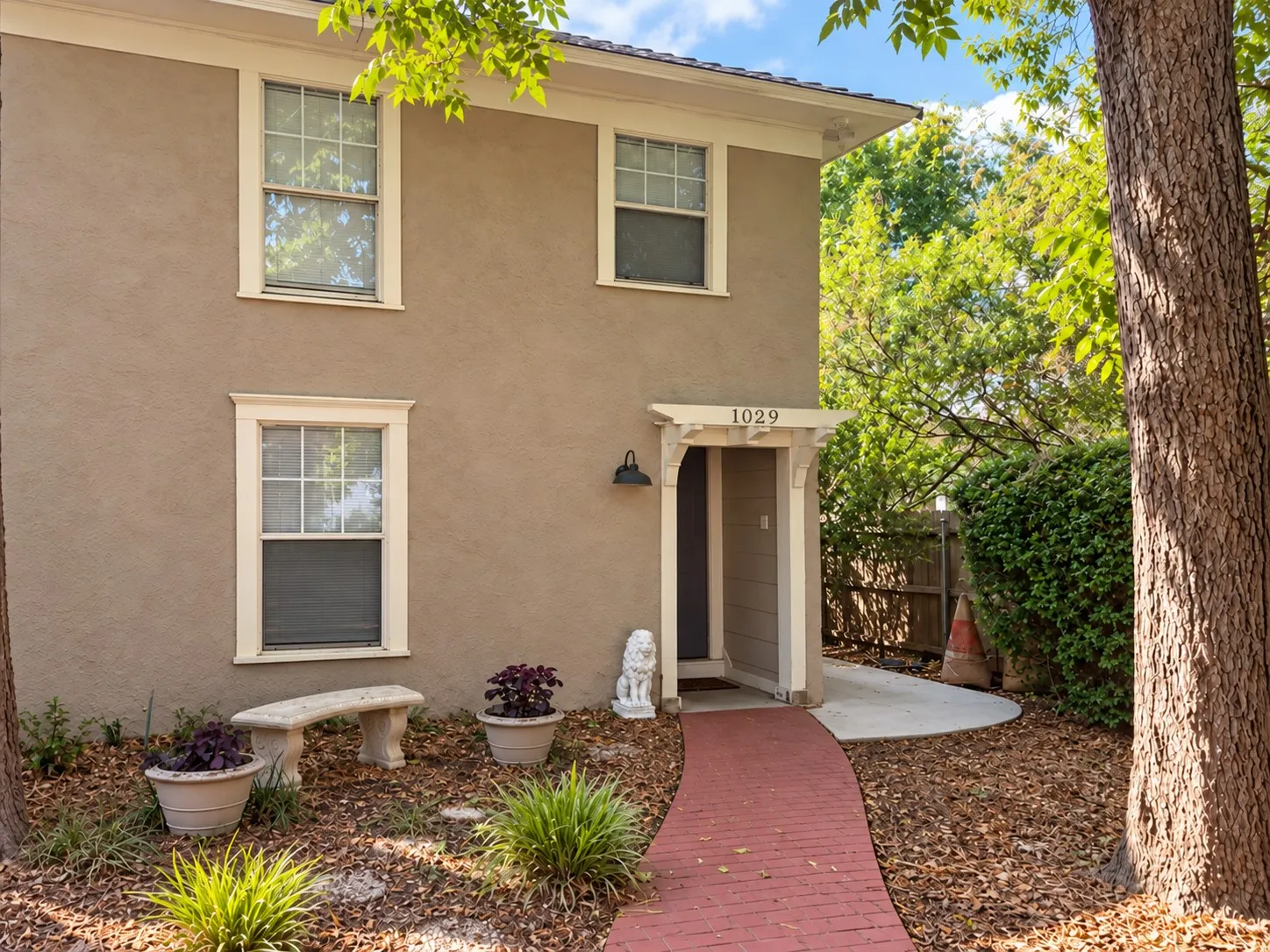 Stucco exterior with white trim windows and a brick pathway