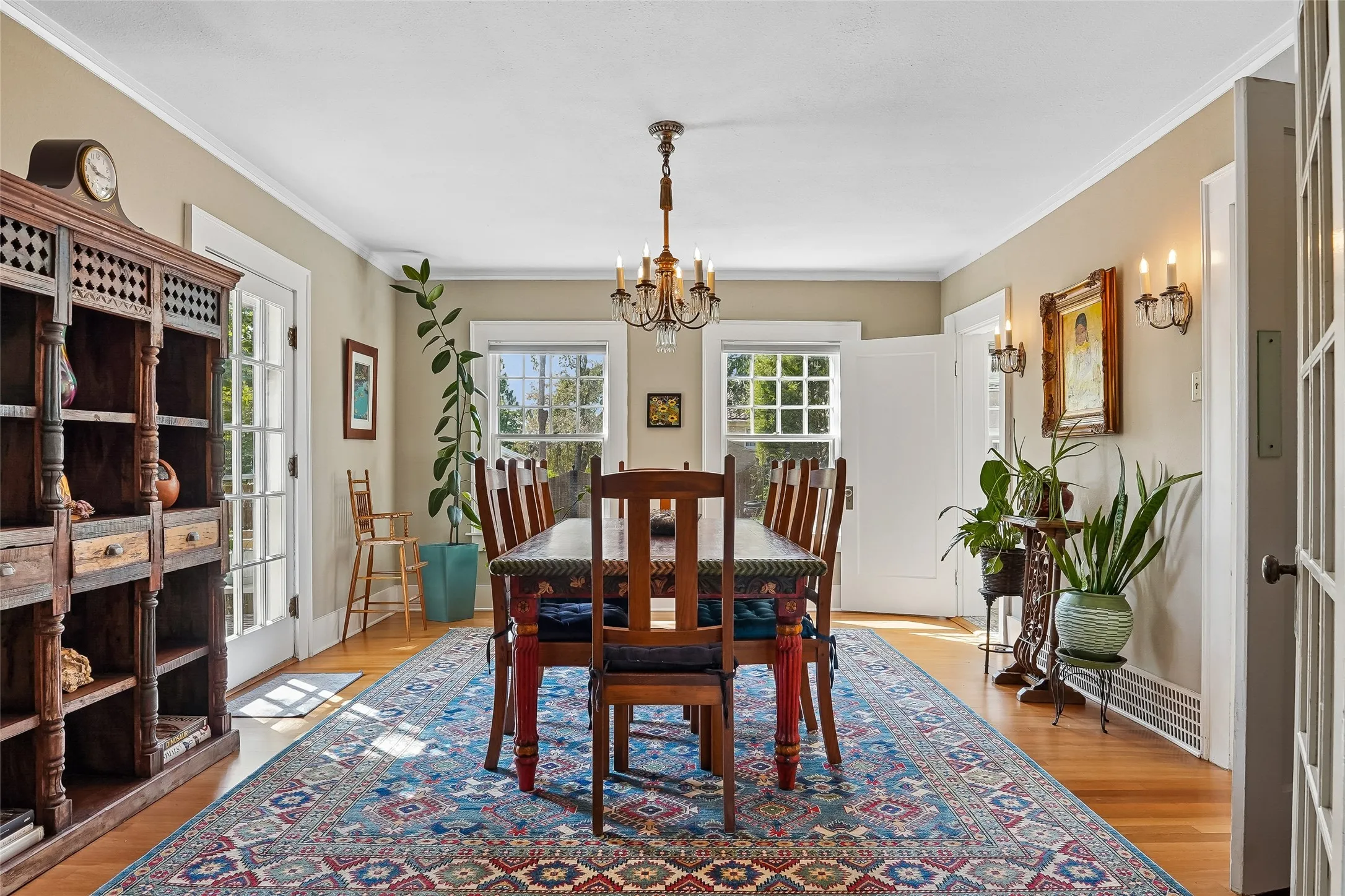 Wood-finish flooring, white trim, multiple windows with natural light, and a chandelier light fixture