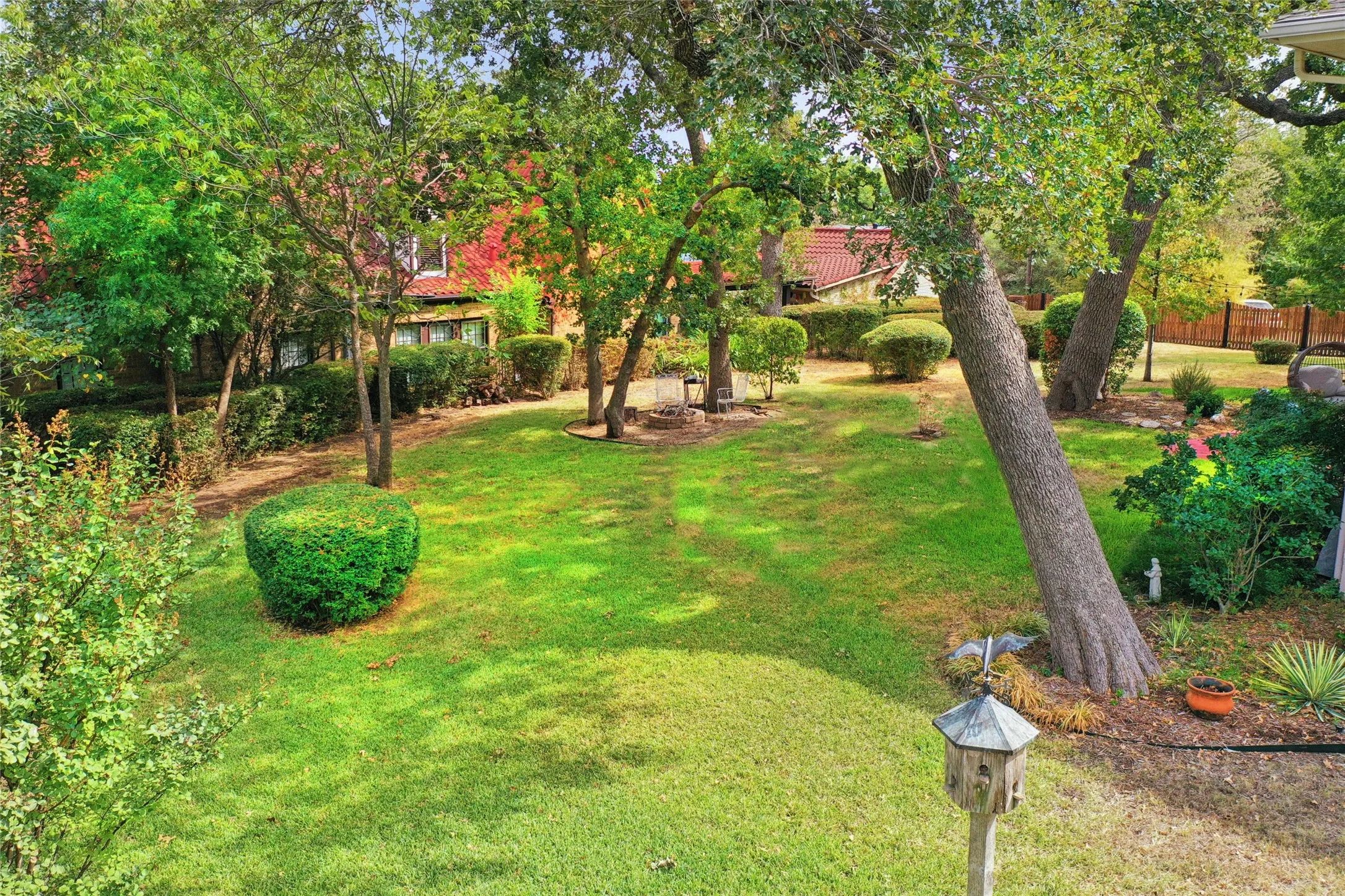Expansive landscaped yard featuring mature trees, manicured lawn, and varied shrubbery