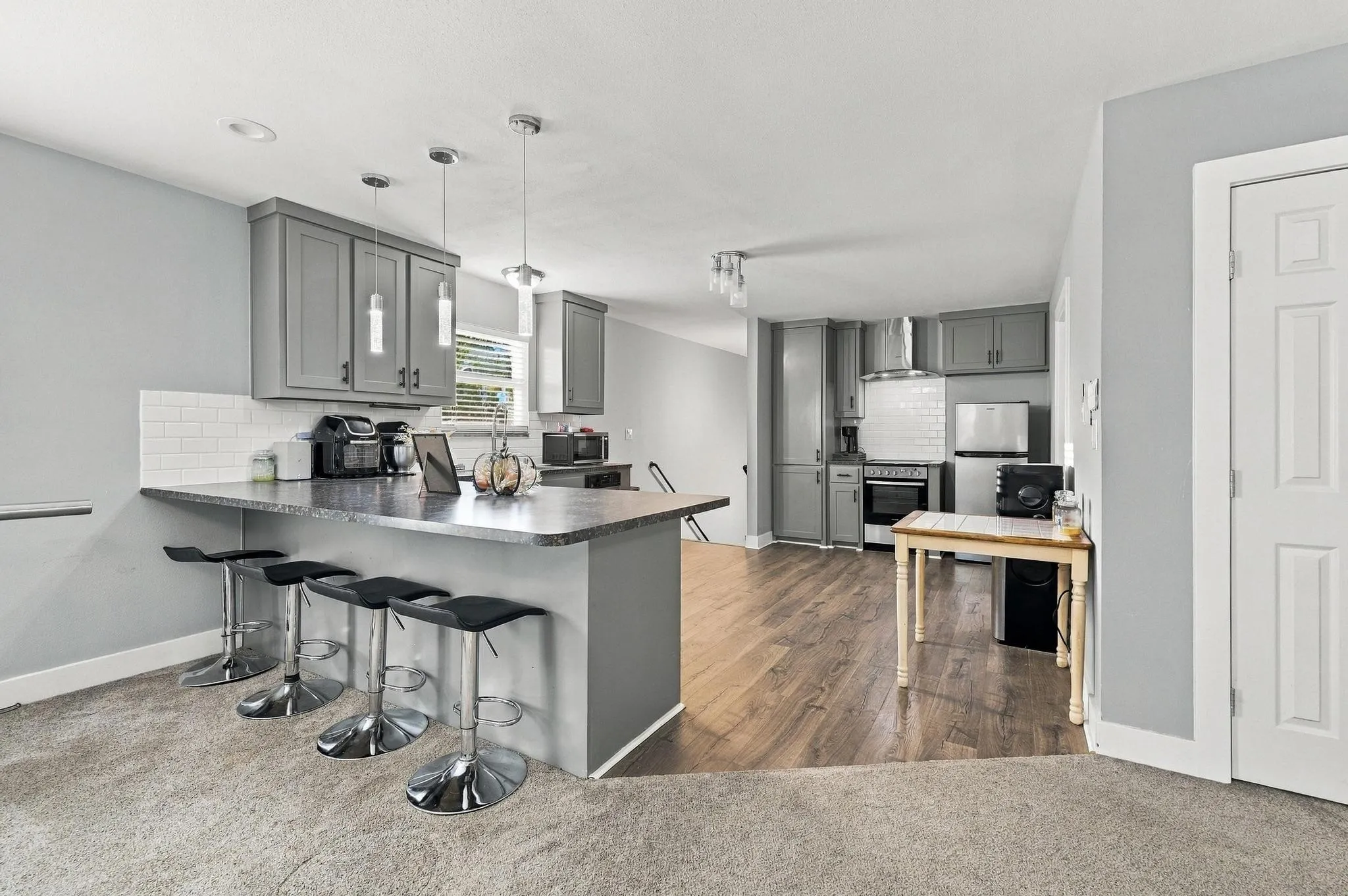 Second Floor Kitchen featuring gray cabinetry, white subway tile backsplash, and a breakfast bar with pendant lighting
