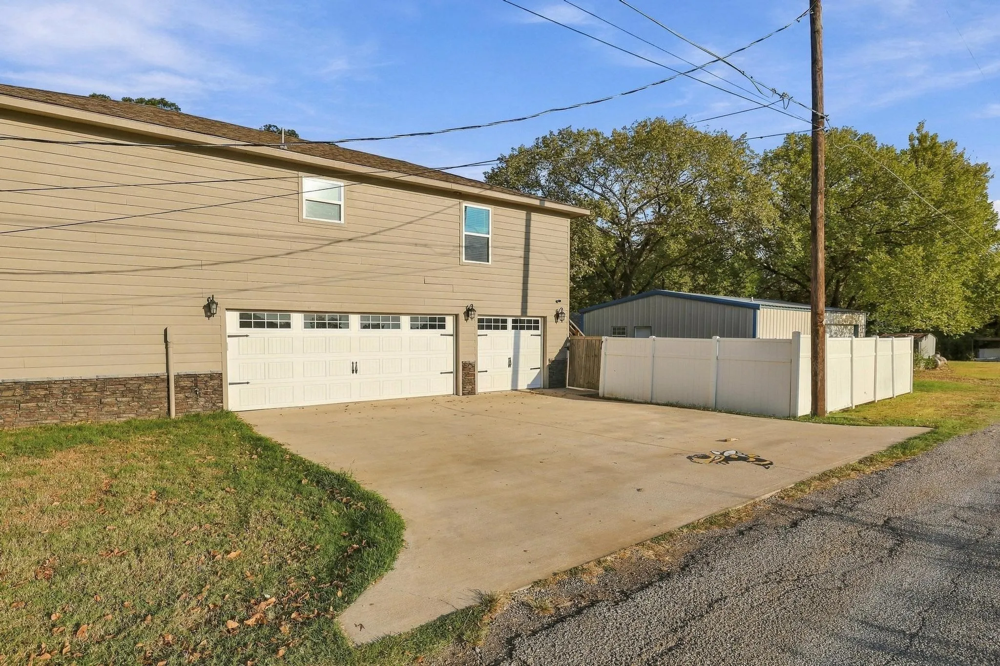 Three-car garage with concrete driveway, vinyl siding exterior, and a privacy fence