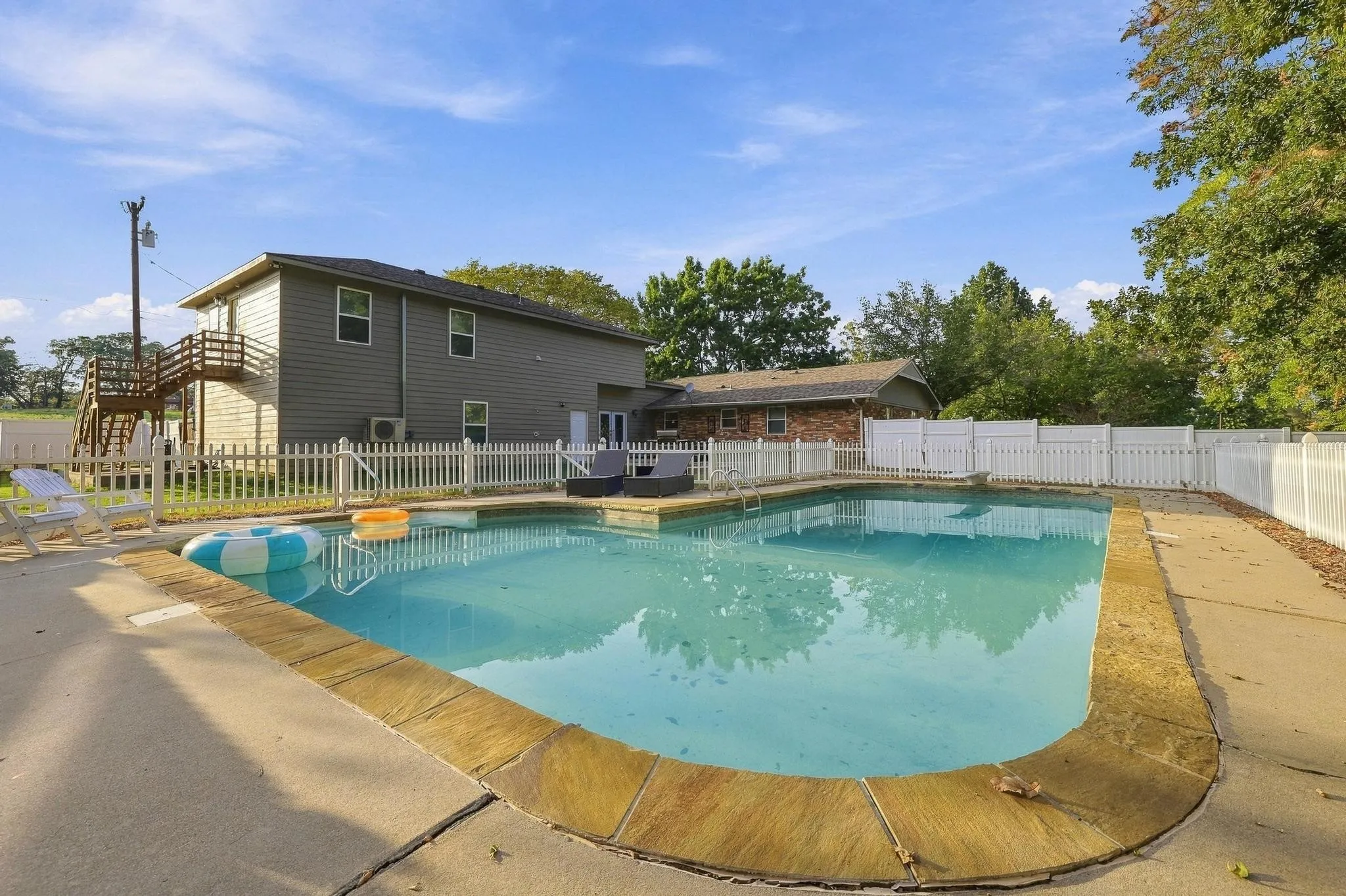 Outdoor swimming pool with concrete decking, and white picket fencing