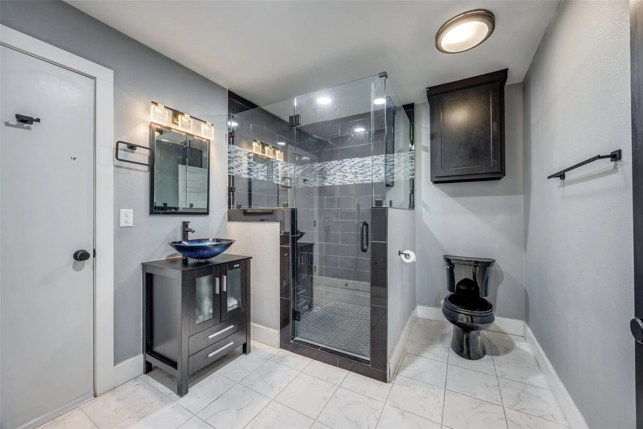 Second Floor Walk-in shower with clear glass enclosure and tile surround, single vanity with vessel sink, wall-mounted mirror with integrated lighting, and white tile flooring