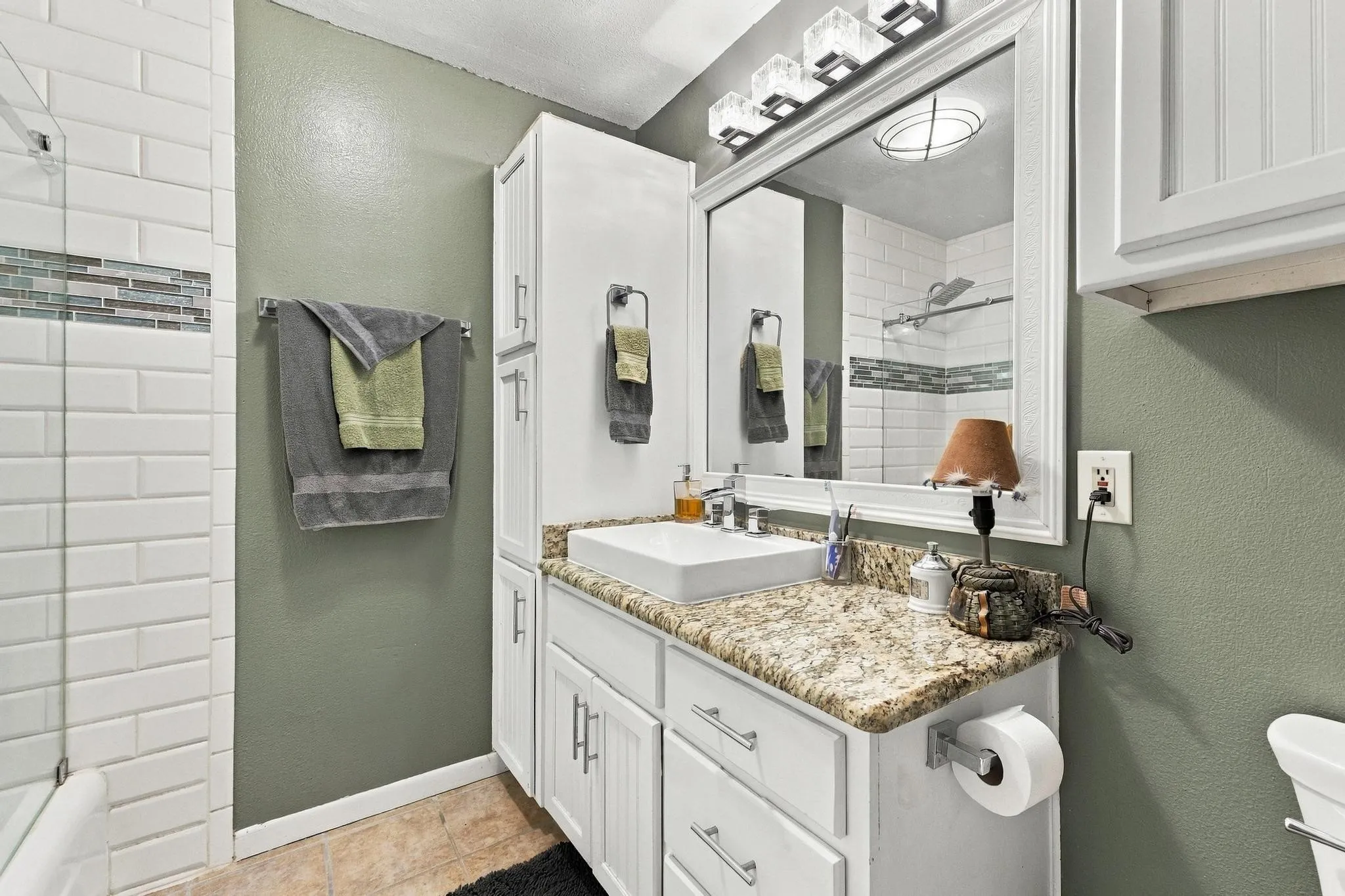 White shaker vanity with a stone-finish countertop and vessel sink