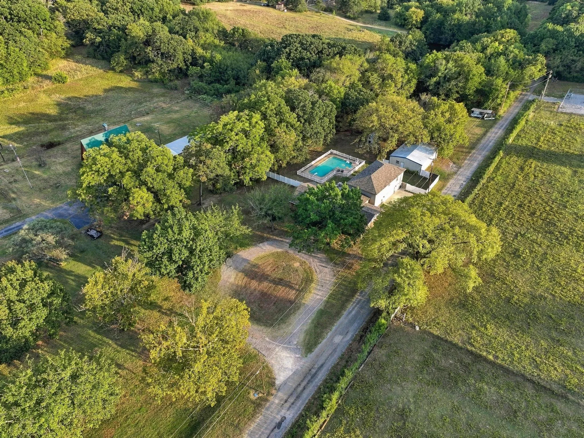 Expansive property featuring a main residence, a swimming pool, and multiple outbuildings, all surrounded by mature trees