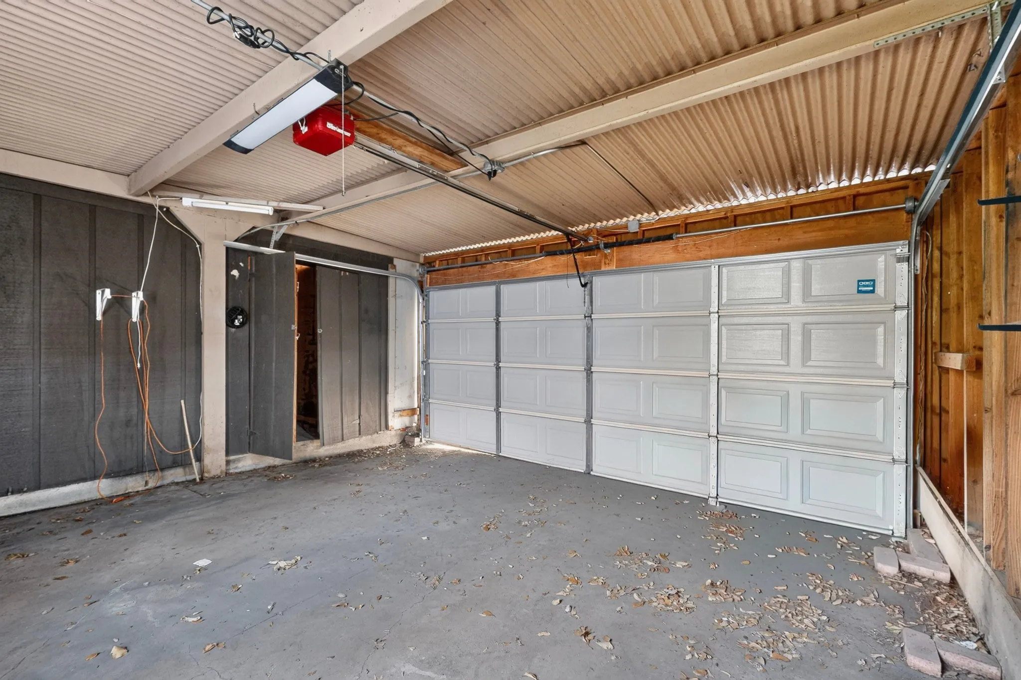 Enclosed garage space with a paneled garage door and corrugated ceiling