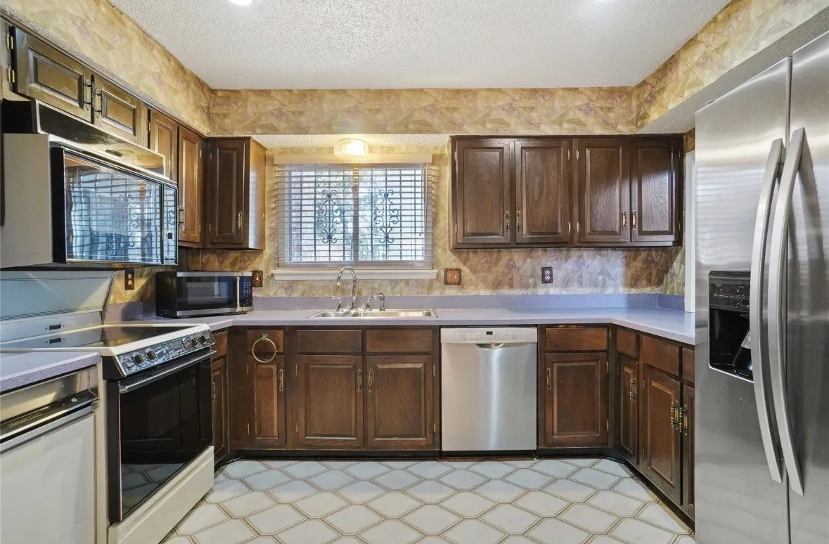 Kitchen featuring wood cabinetry, stainless steel appliances, and patterned floor