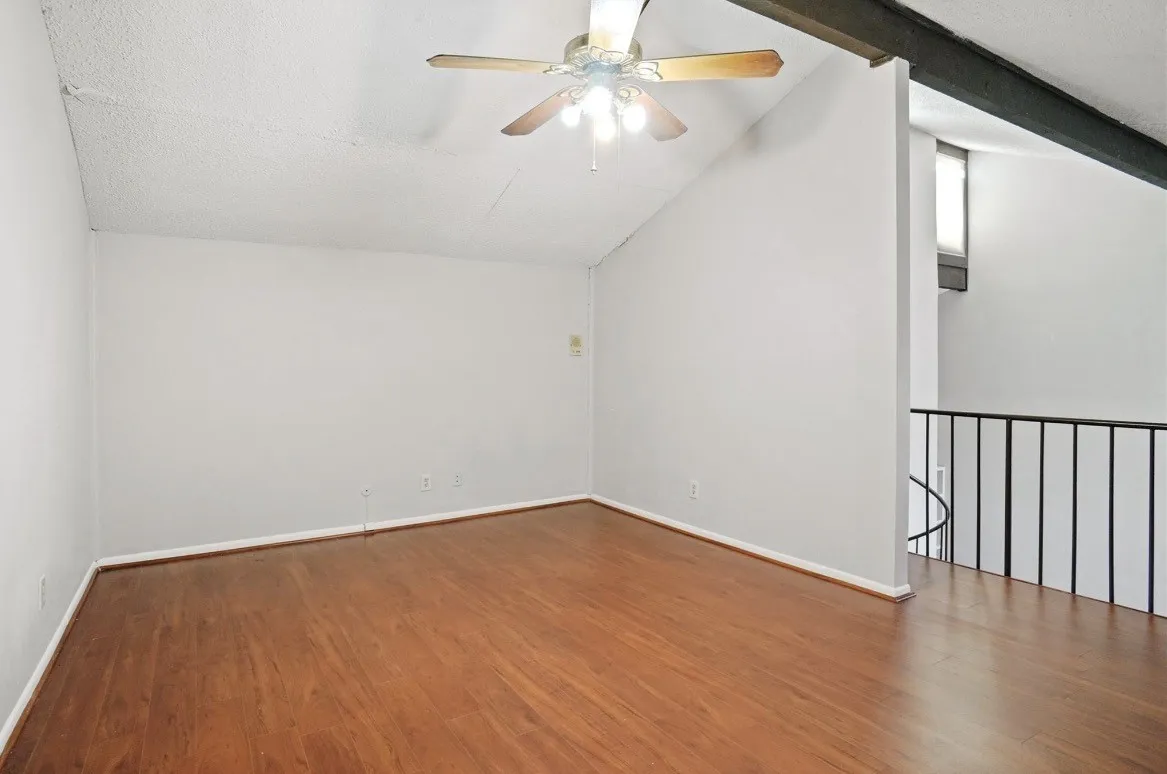 Upstairs flex room; Vaulted ceiling with exposed beam, wood-finish flooring, and a ceiling fan