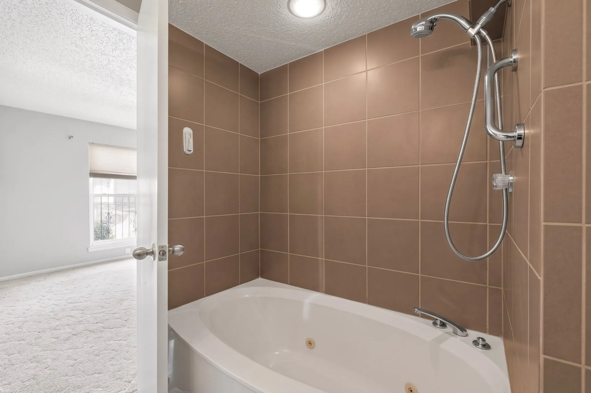 Built-in jetted tub with chrome fixtures and handheld shower