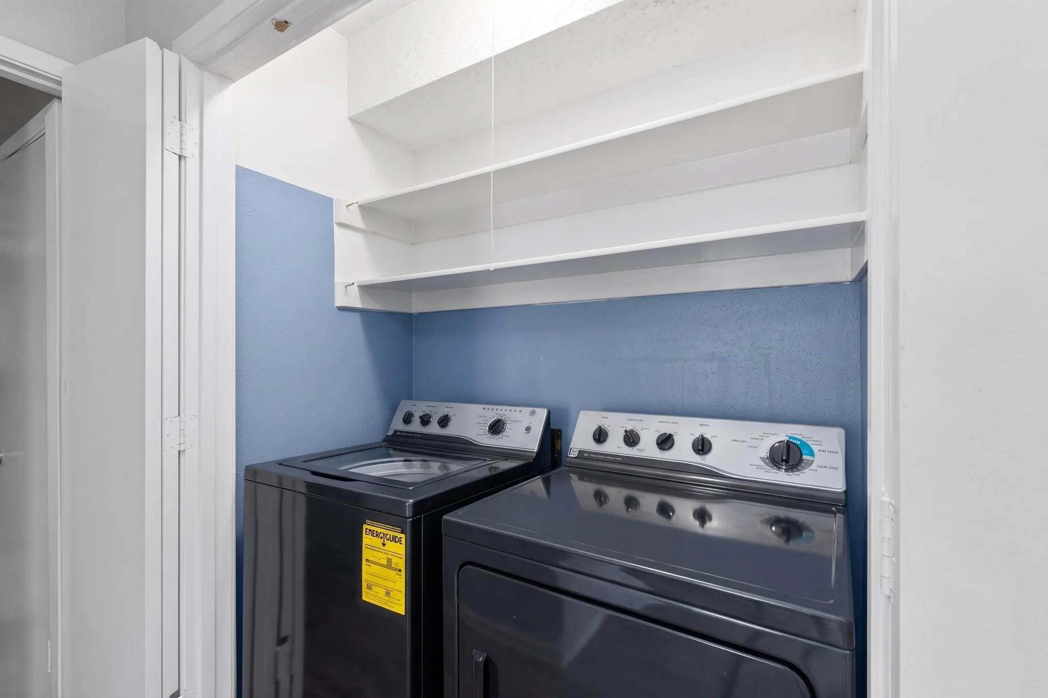Laundry area with built-in shelving and appliances