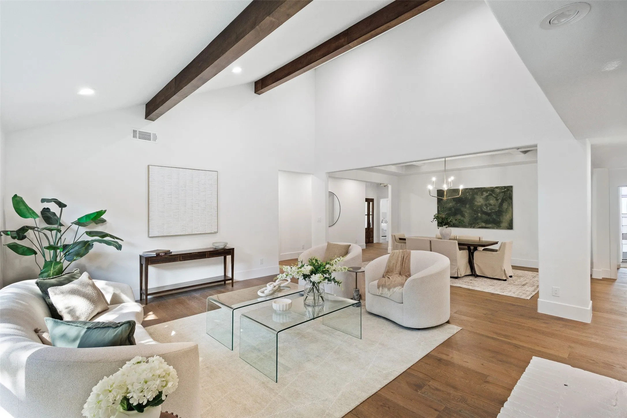 Vaulted ceiling with exposed wood beams, recessed lighting, and wood-finish flooring