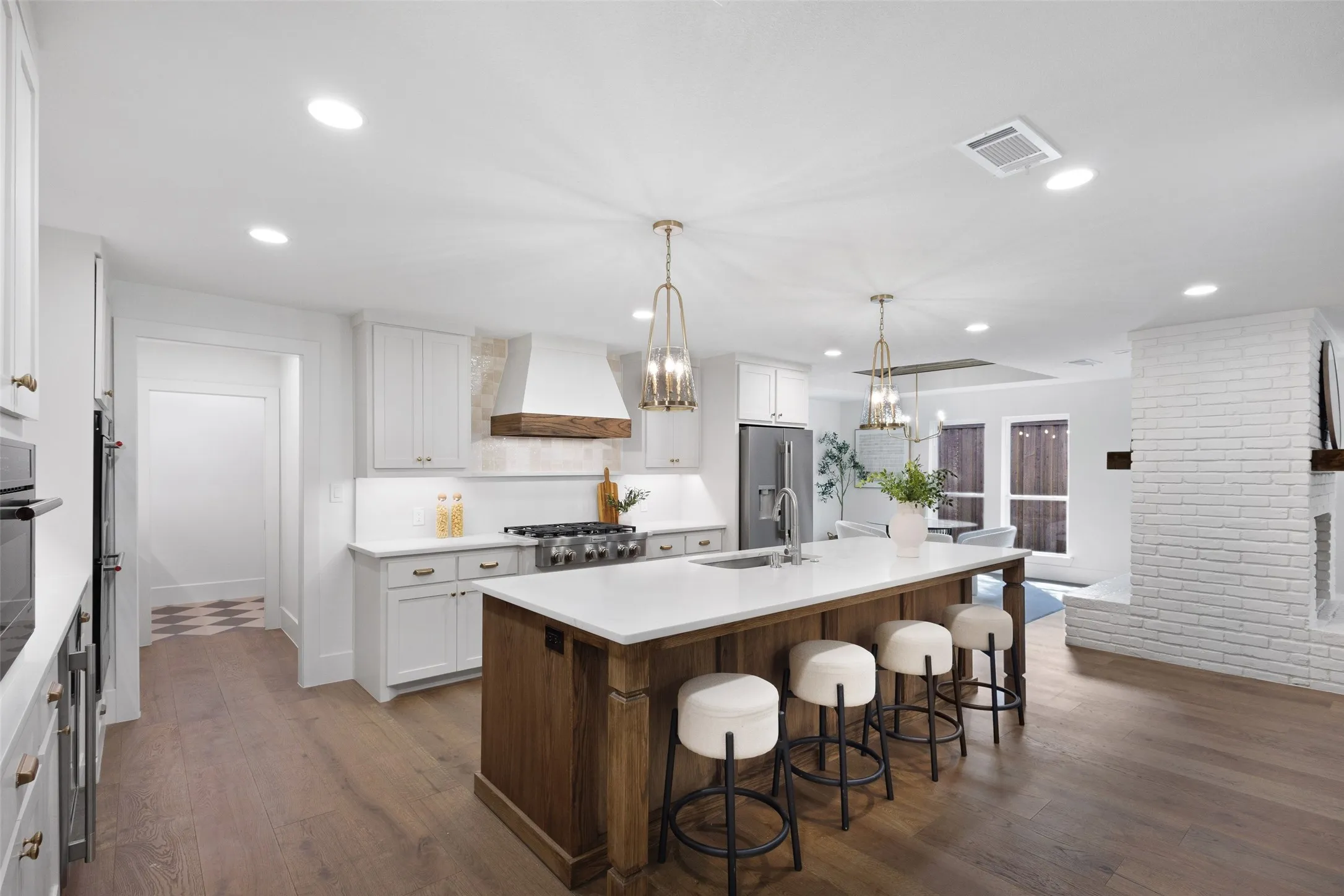 Gourmet kitchen featuring a large island with seating, stainless steel appliances, white cabinetry, and wood-finish flooring