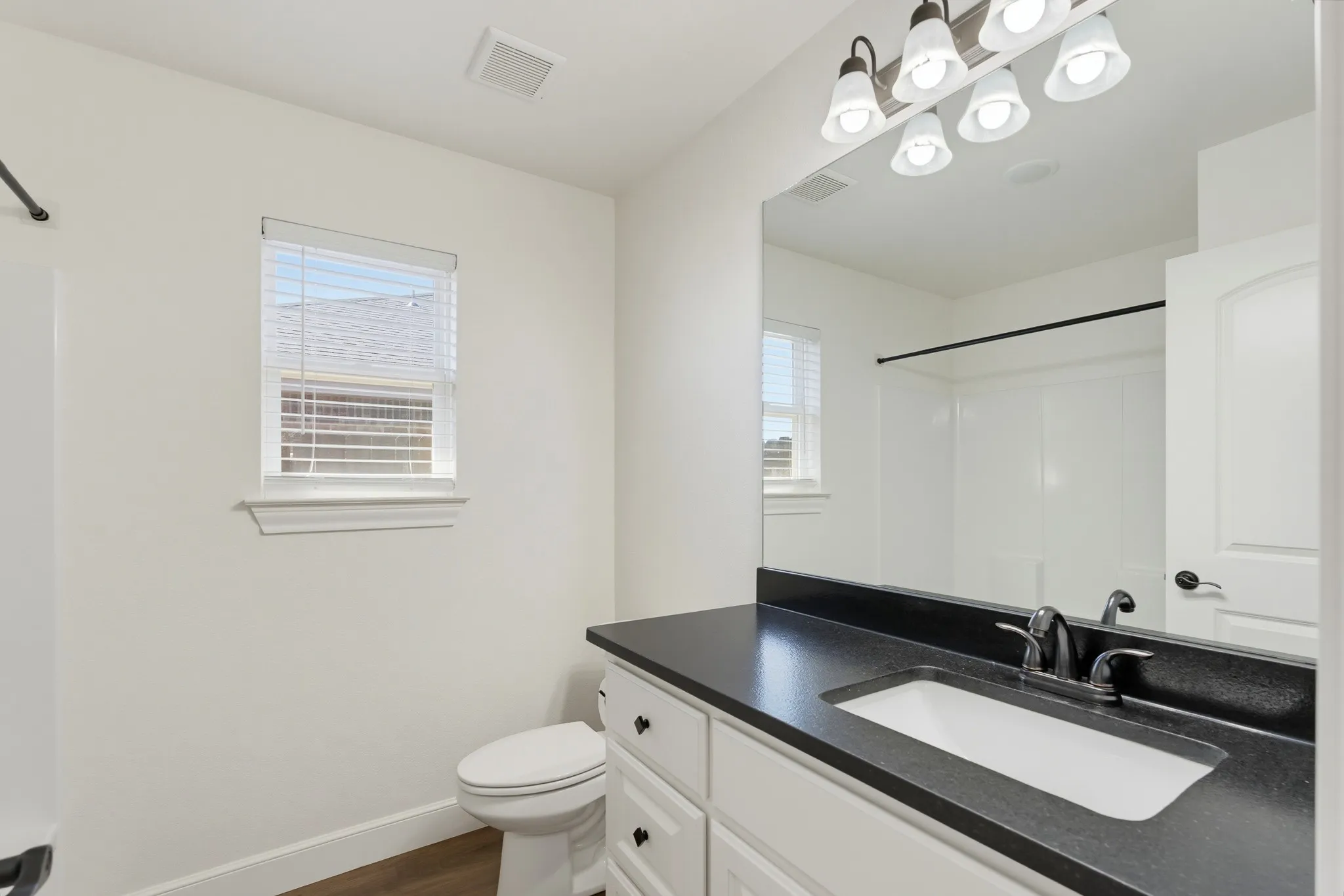 White vanity with a dark countertop and integrated sink