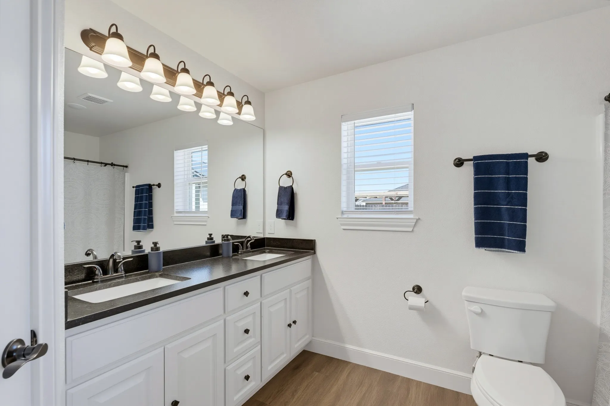Dual vanity with integrated sinks, dark countertop, and ample storage cabinetry