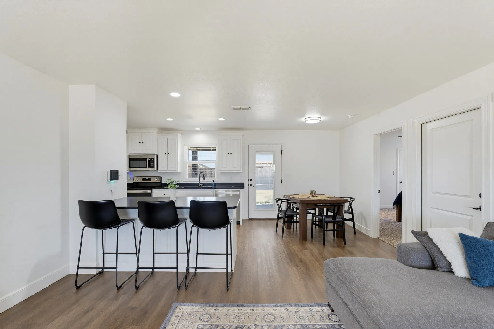 Open-concept living area with wood-finish flooring, recessed lighting, and white walls