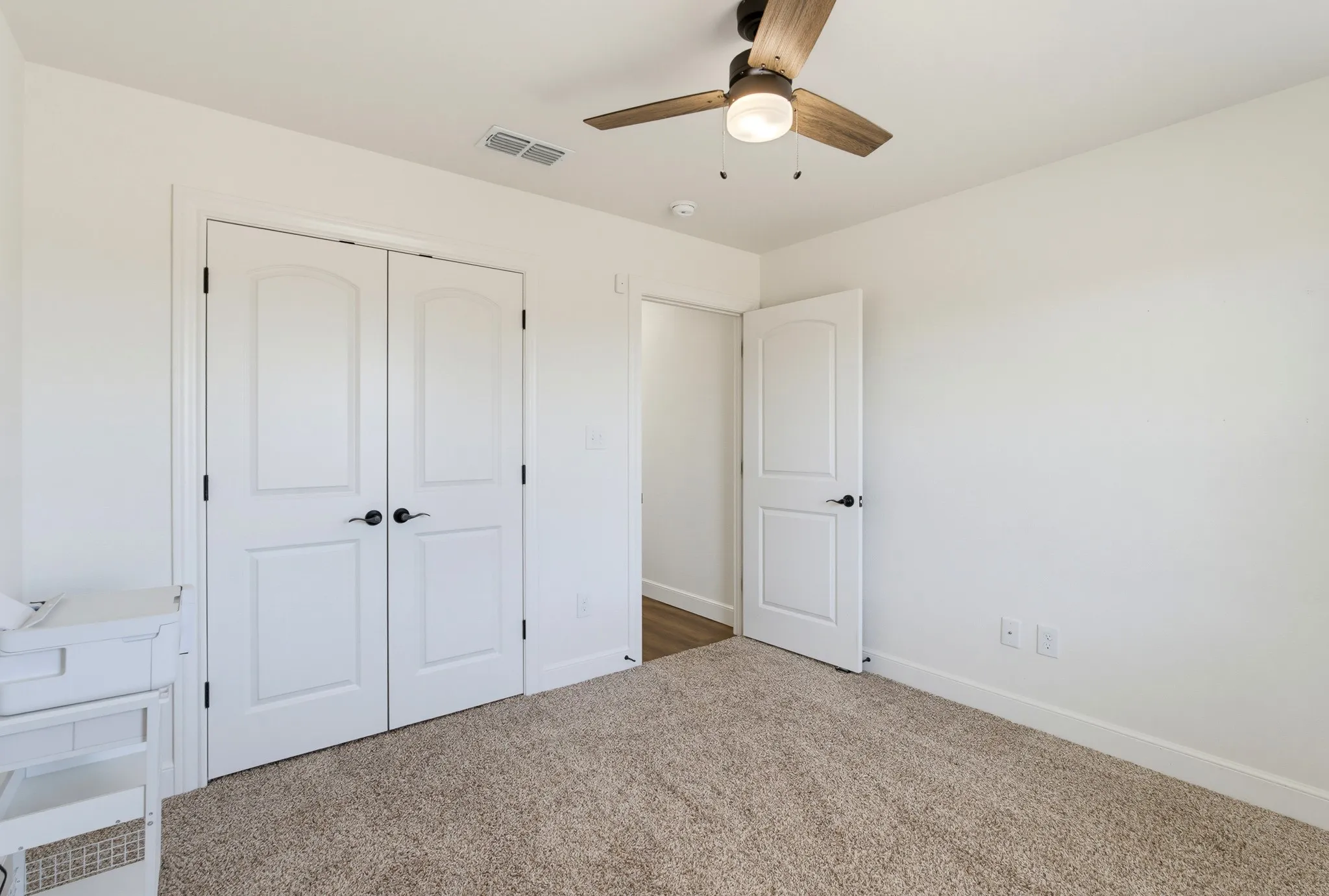 Neutral wall color, ceiling fan with light fixture, double-door closet, and carpeted flooring