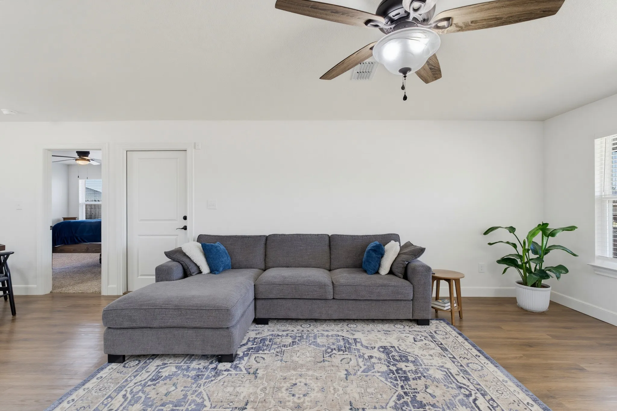 Recessed lighting, wood-finish flooring, white walls, ceiling fan with light fixture, and window with blinds